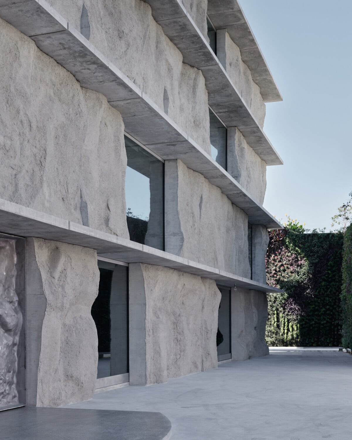Auf der Vorderseite hingegen ist ein kleiner Platz mit einer Vorfahrt angelegt. Ein vertikaler Garten von Patrick Blanc, der diesen Bereich flankiert, war für den Namen Green Corner Building ausschlaggebend.