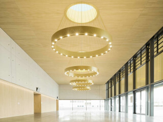 Das dreigliedrige Gebäudevolumen nach Plänen von Lamott.Lamott Architekten zeigt sich einladend und repräsentativ, arrangiert um einen erhöhten öffentlichen Platz. 