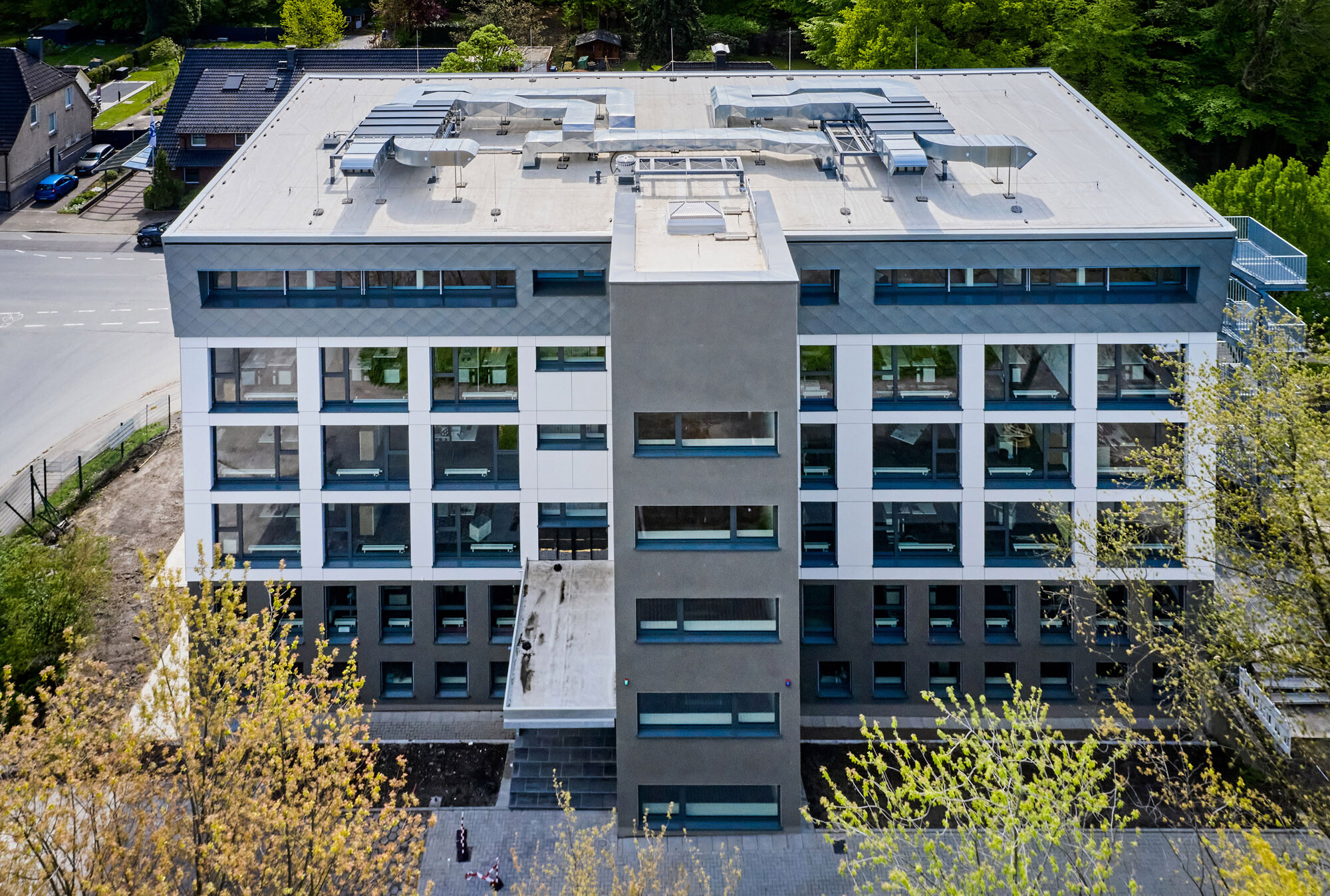 Während die Sockelgeschosse und der Treppenhausturm mit einem Wärmedämmverbundsystem und dunkelgrauem Kratzputz versehen wurden, rahmt eine vorgehängte Fassade die großen Fenster der drei folgenden Geschosse. Die Aufstockung erhielt auf drei Seiten eine verzinkte Bekleidung.