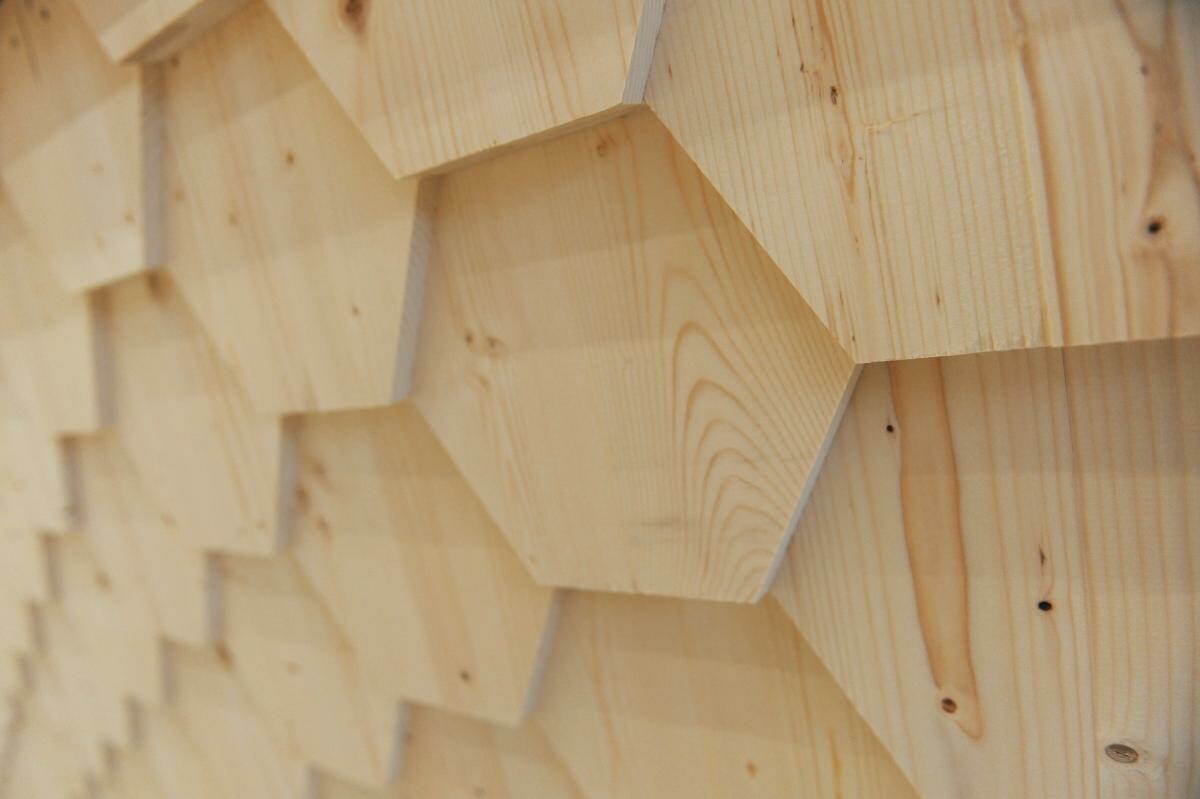 Als Bekleidung dienen wabenförmige Holzschindeln, die überlappend angeordnet sind.