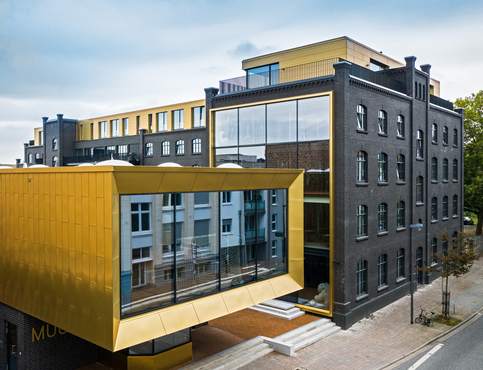 Bei dem L-förmige Fabrikgebäude und dem Pförtnerhaus (vorne im Bild) handelt es sich um Backsteinbauten aus dem Jahr 1897, die unter Ensembleschutz stehen.