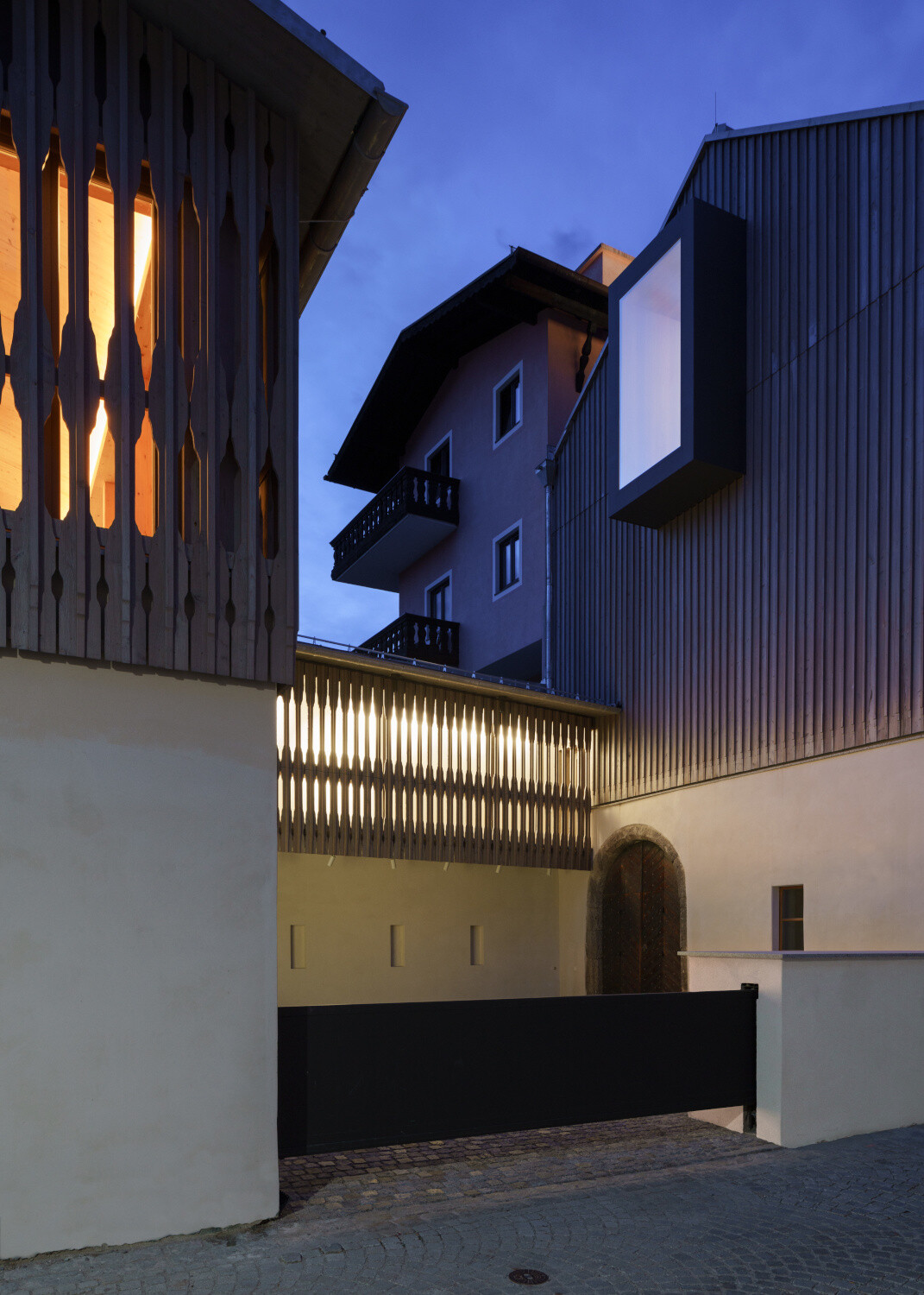 Die Aufstockung ist eine Holzkonstruktion. Die Holzfassade wird beim abgerückten Neubau und dessen Verbindung in variierter Form aufgenommen.
