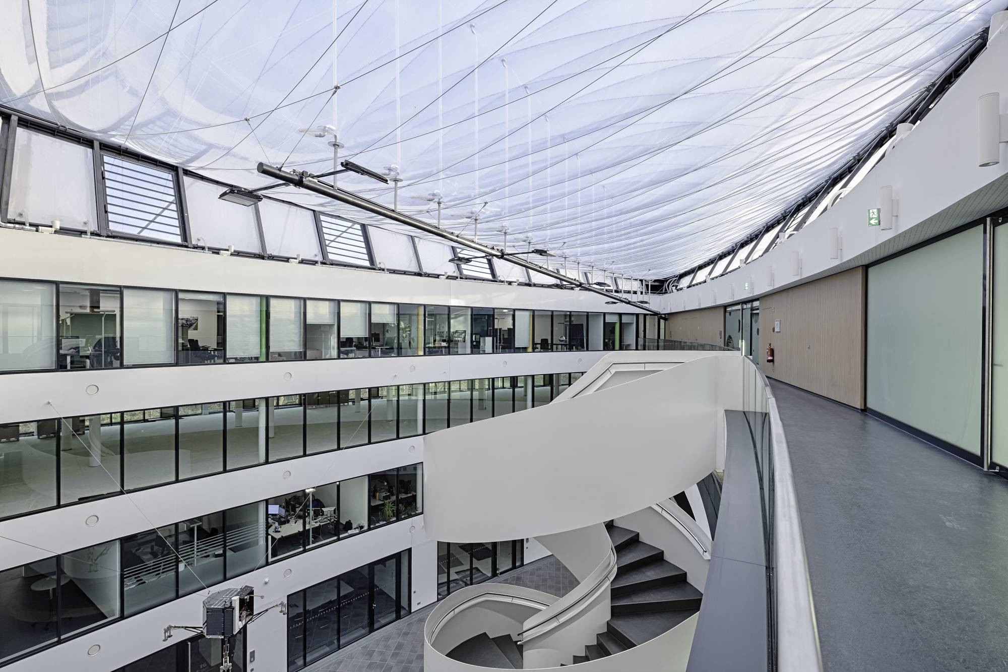Neben dem Hightech-Dach aus ETFE-Folie fungiert eine frei stehende Wendeltreppe aus weiß lackiertem Stahl im Atrium als Blickfang.
