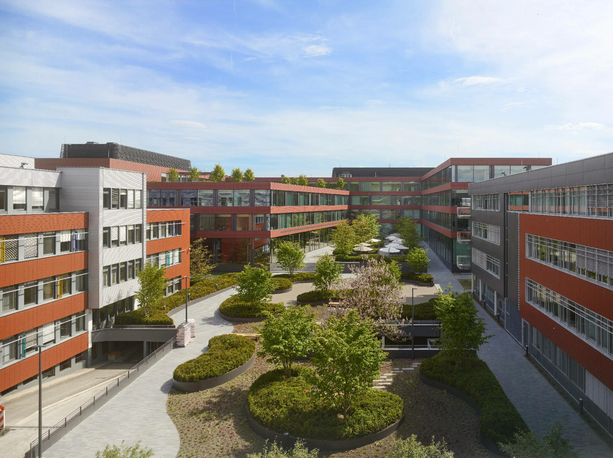 Mit der 2016 errichteten Firmenzentrale südlich der bestehenden vier Gebäude ist ein Campus entstanden, der eine parkähnliche Grünanlage umschließt (Blick gen Süden).