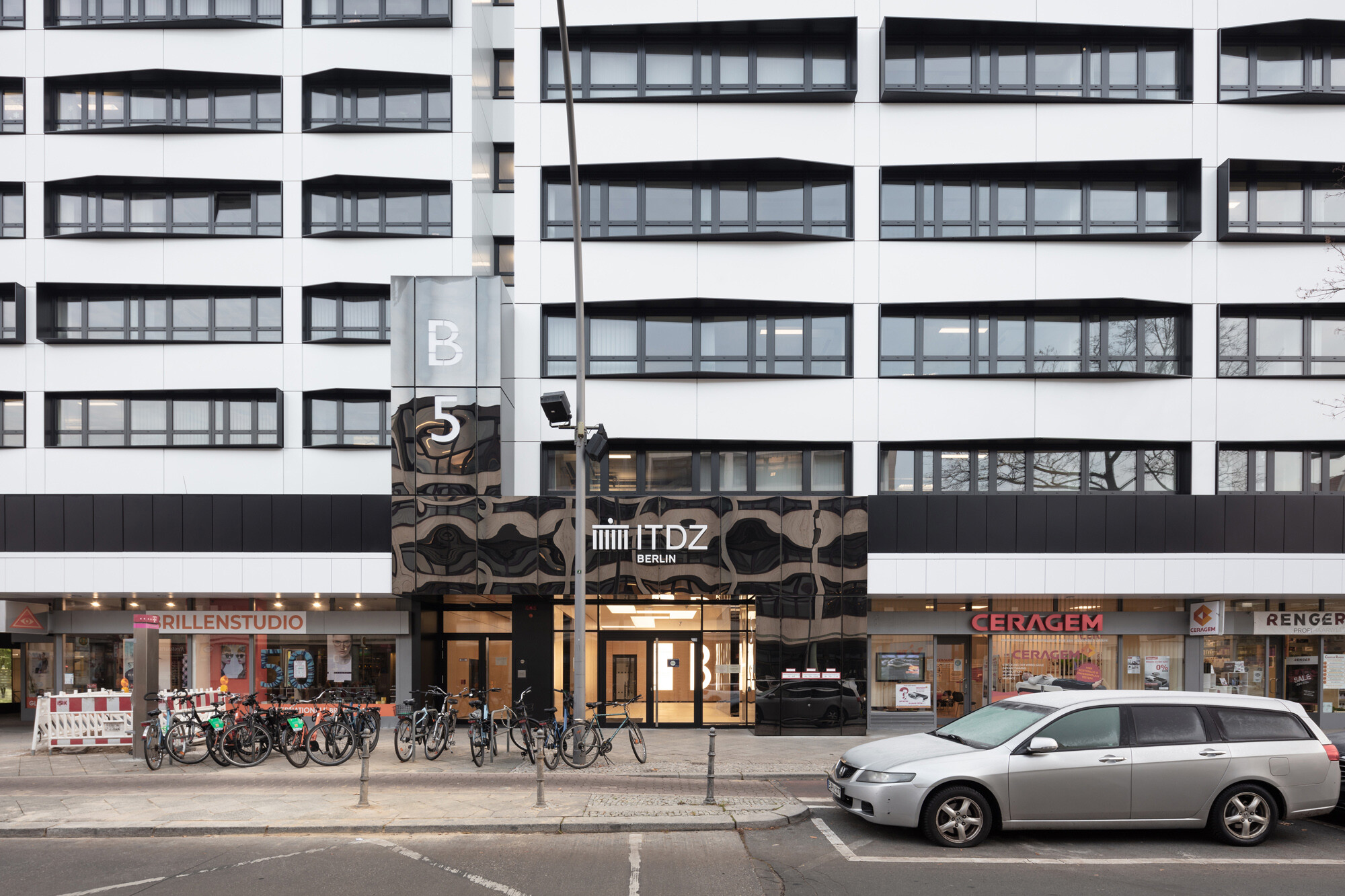 Eine neue, hinterlüftete, vorgehängte Fassade, bestehend aus großformatigen, pulverbeschichteten, weißen Aluminiumblechkassetten ersetzt die vormals schmucklose graue Bestandshülle. 