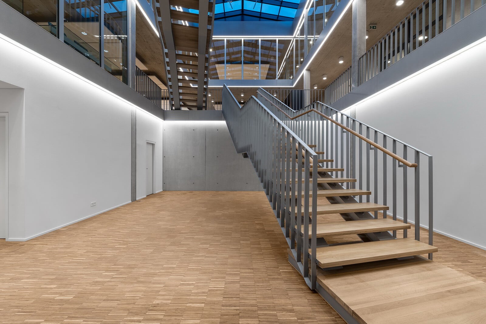 Im Innenraum erfolgt die Erschließung über ein gebäudehohes Atrium, in dem die beiden Treppenläufe frei angeordnet sind.