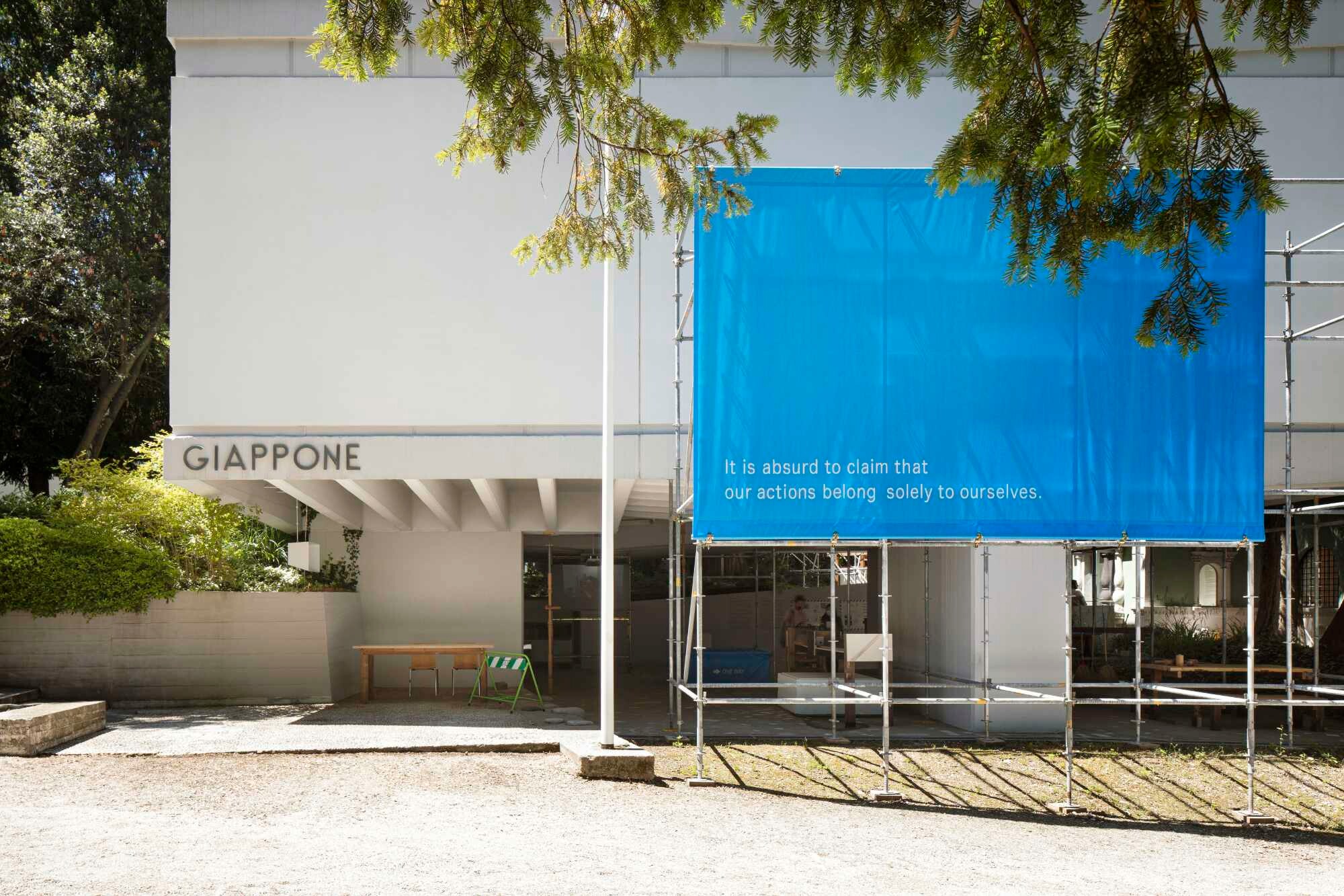 Das zentrale Motto des japanischen Beitrags trägt ein Banner, das die Besuchenden vor dem Pavillon empfängt und an einem Gerüst befestigt ist.