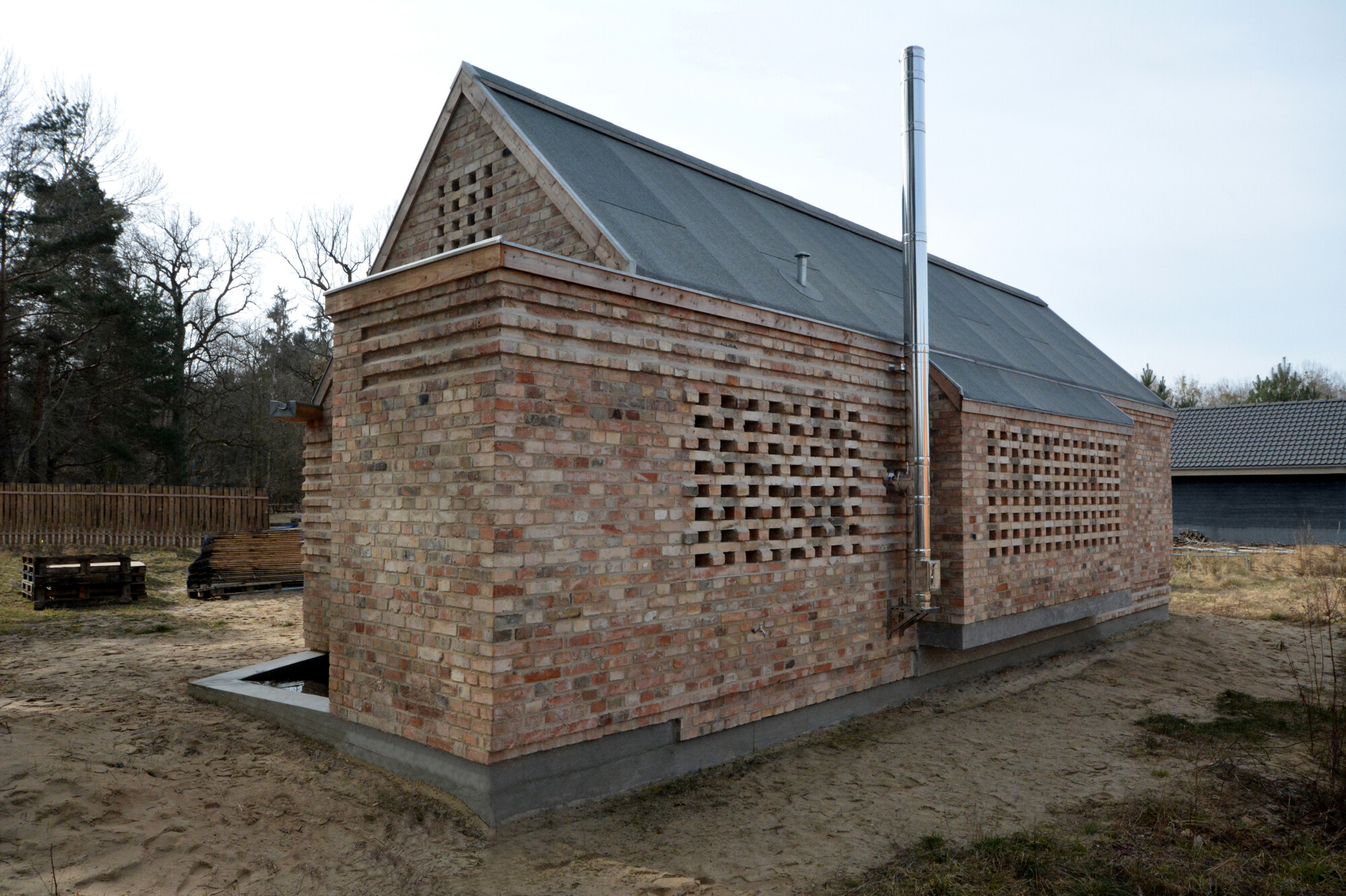 Die verschiedenen Farbtöne der recycelten Ziegel lassen die Fassade rötlich, gelblich und gräulich schimmern. 