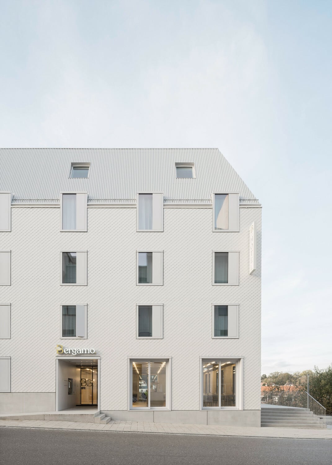 Die Gebäudehülle besteht aus Faserzementschindeln an den Fassaden sowie Aluminium-Trapezblechen im Dachbereich.
