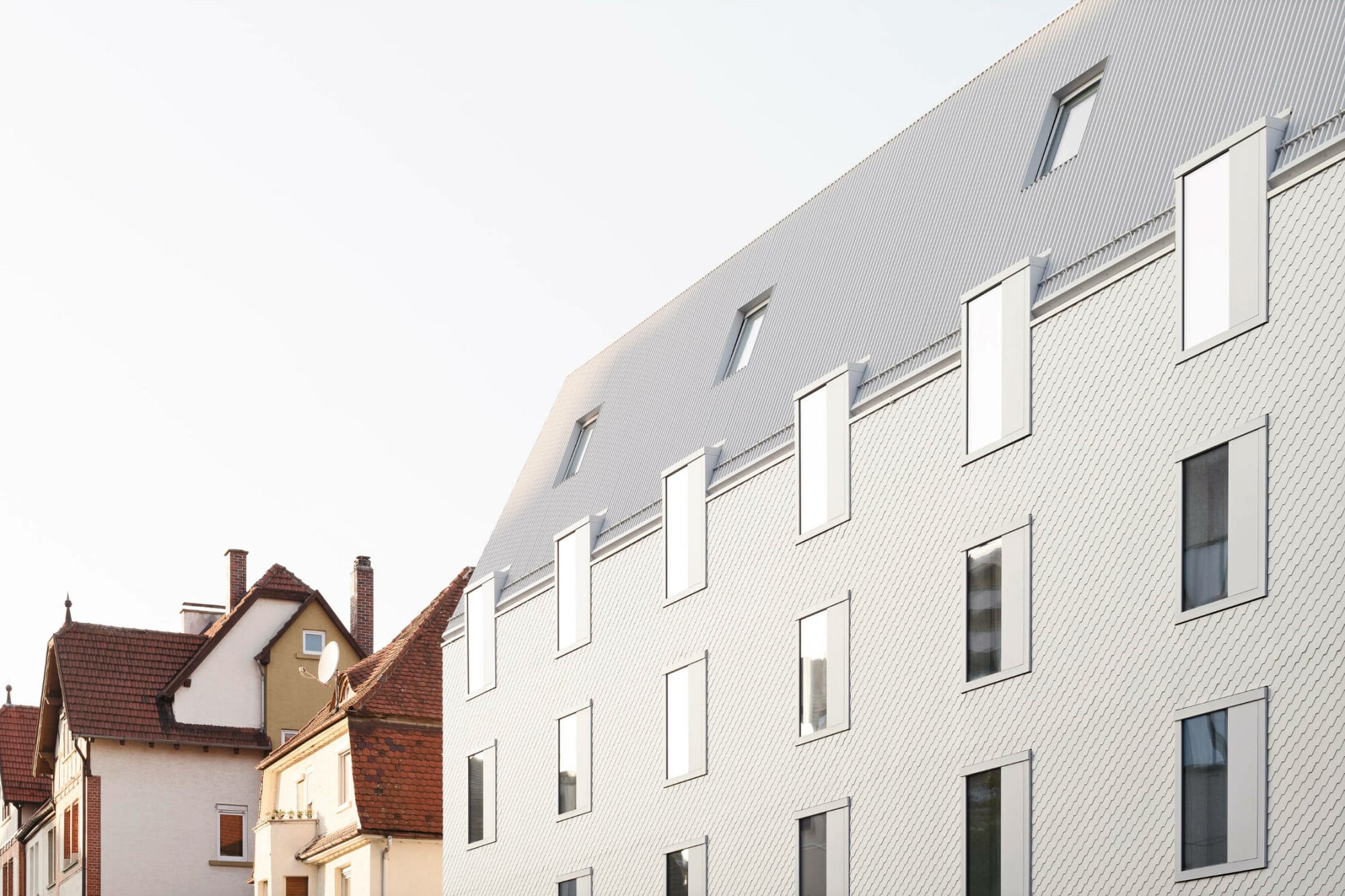 Die Fenster sind fassadenbündig, im 3. OG ragen sie senkrecht über die Traufe hinaus. 