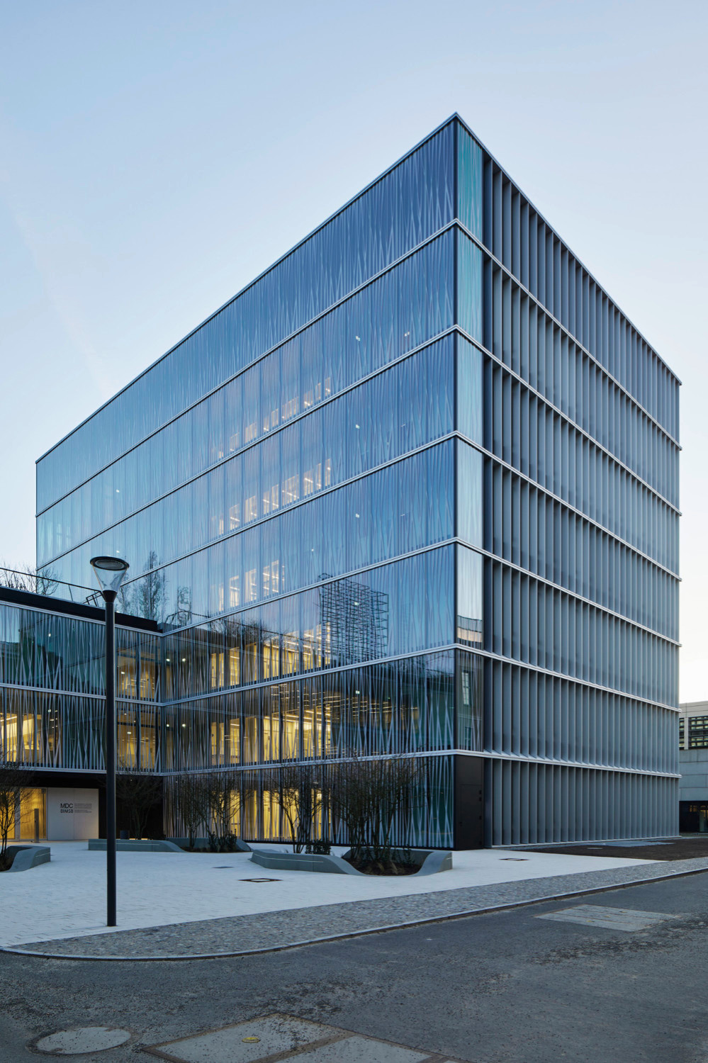 Staab Architekten entwarfen das Laborgebäude mit bedruckter Glasfassade und einem L-förmigen Grundriss.
