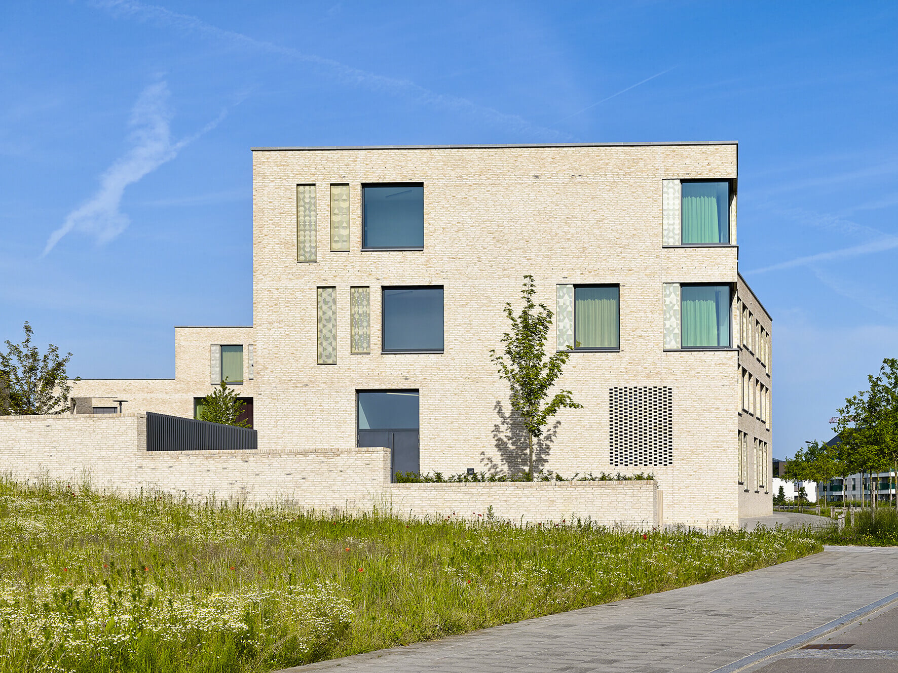 Ein Highlight des Projektes ist aber die haptisch interessante Fassade aus handgestrichenen, gelben Ziegelsteinen im Dünnformat. Je nach Sonnenstand treten die unterschiedlichen Farbnuancen und unregelmäßigen Oberflächen mehr oder weniger stark hervor und erzeugen ein abwechslungsreiches Licht- und Schattenspiel. 