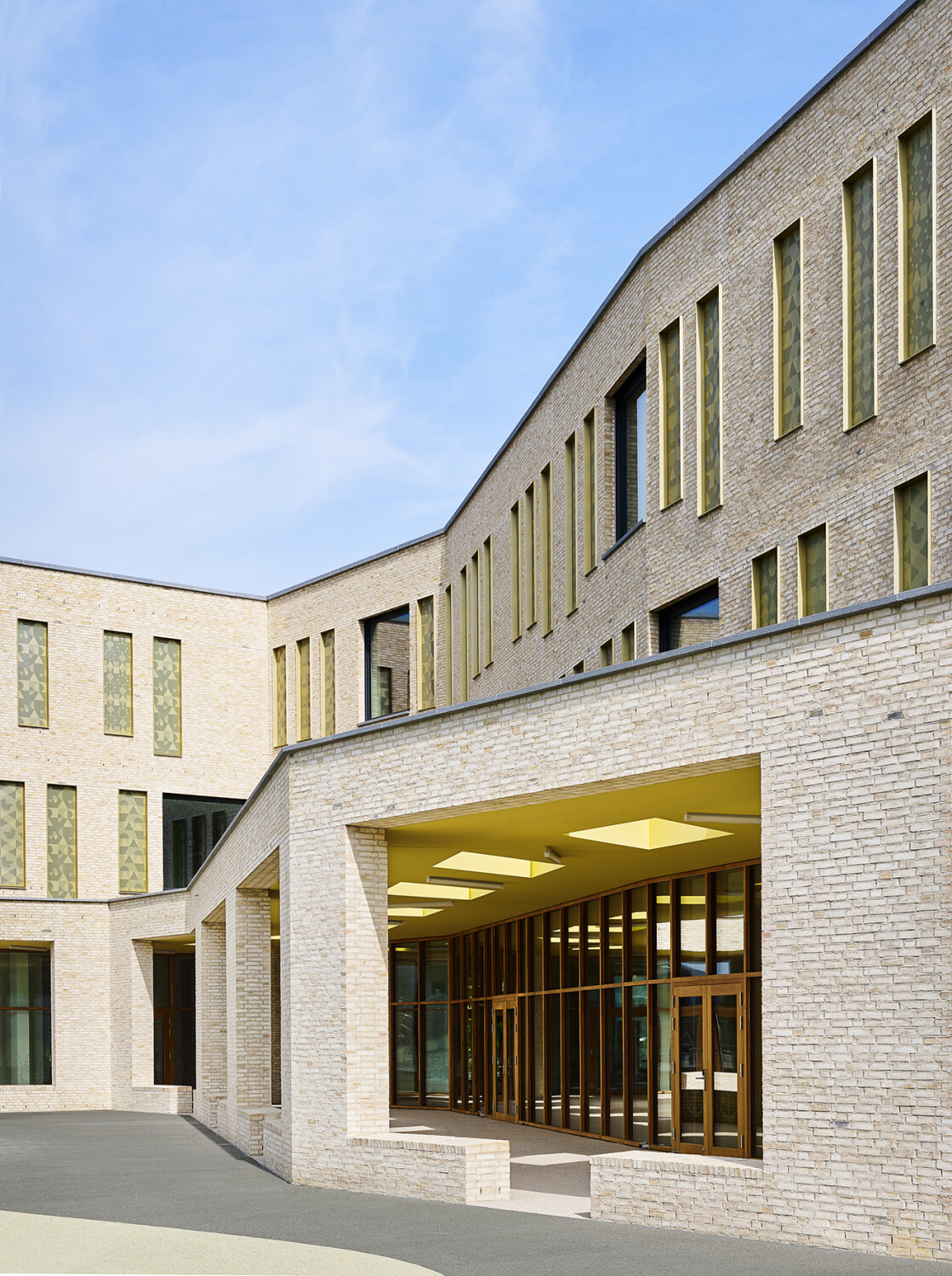 Zur Straße ragt das Gebäude mit drei Geschossen in die Höhe, zum Hof hin treppt es sich ab und mündet in einer Art eingeschossigen Pergola, die einen Transitbereich zwischen Außen und Innen darstellt.