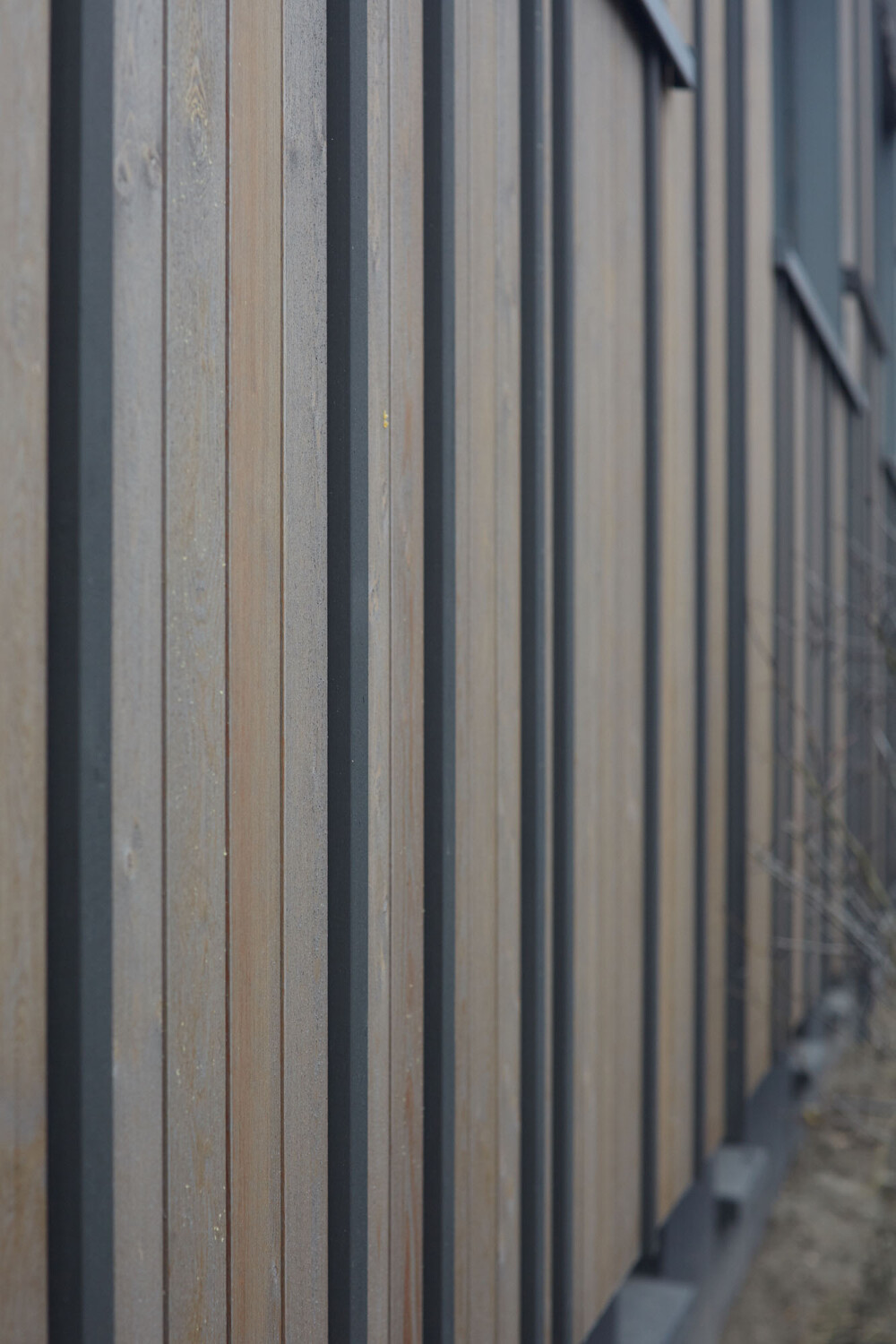 Vertikale Latten aus Lärchenholz strukturieren die Fassade des sanierten Gebäudes.