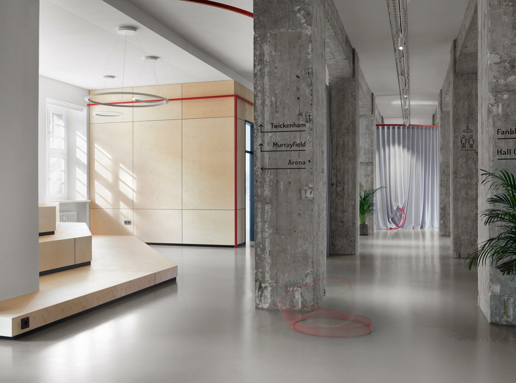 Einbauelemente aus Birkenholz, Vorhänge in gedeckten und leuchtenden Blautönen und Akzente aus feuerrot beschichtetem Stahl bestimmen das Bild des Co-Working Space.