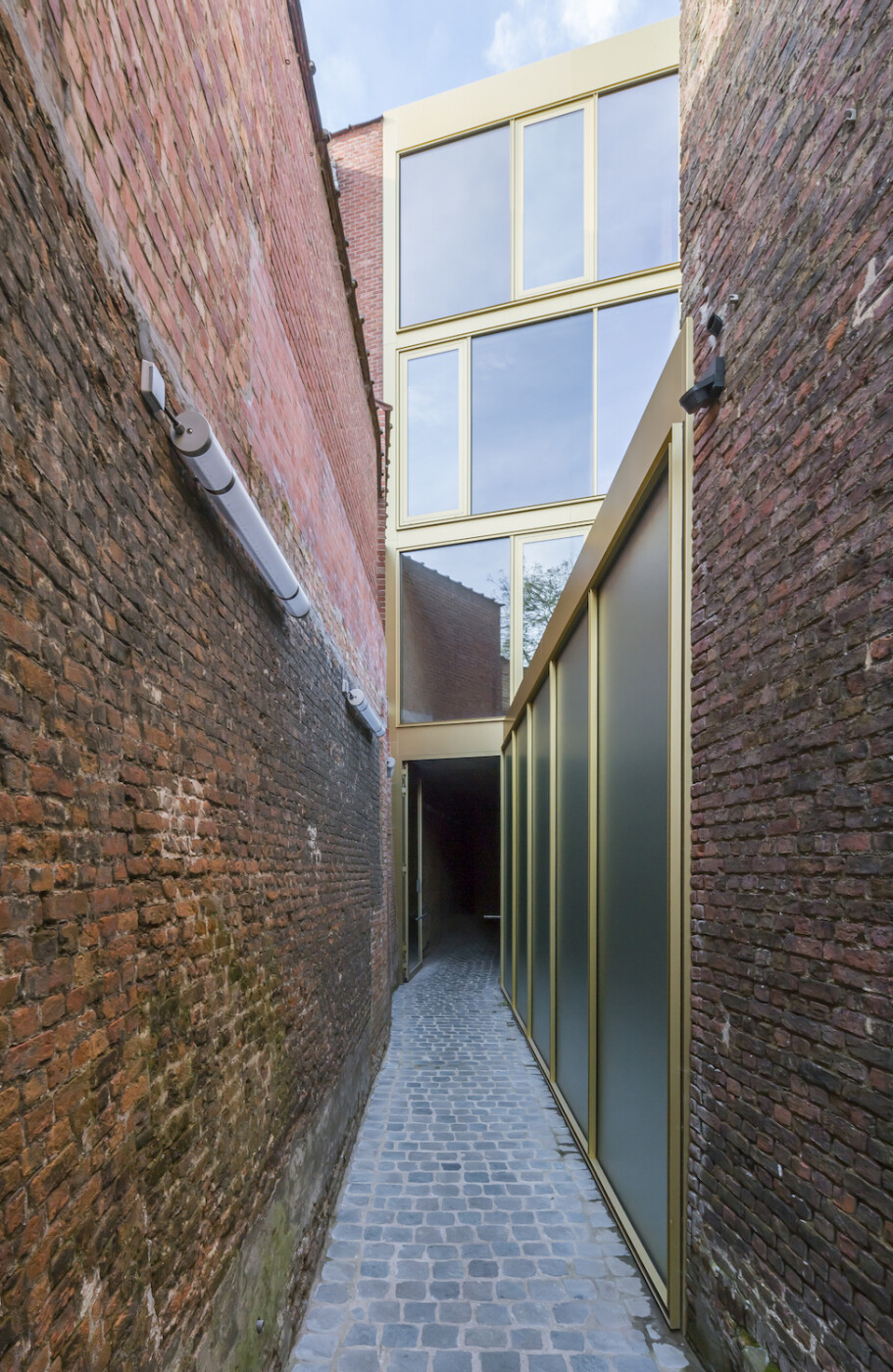 Der gläserne Eingangsbau bildet den Auftakt zu einer Gasse, die die verschiedenen Nutzungen, Bestands- und Neubauten verbindet.