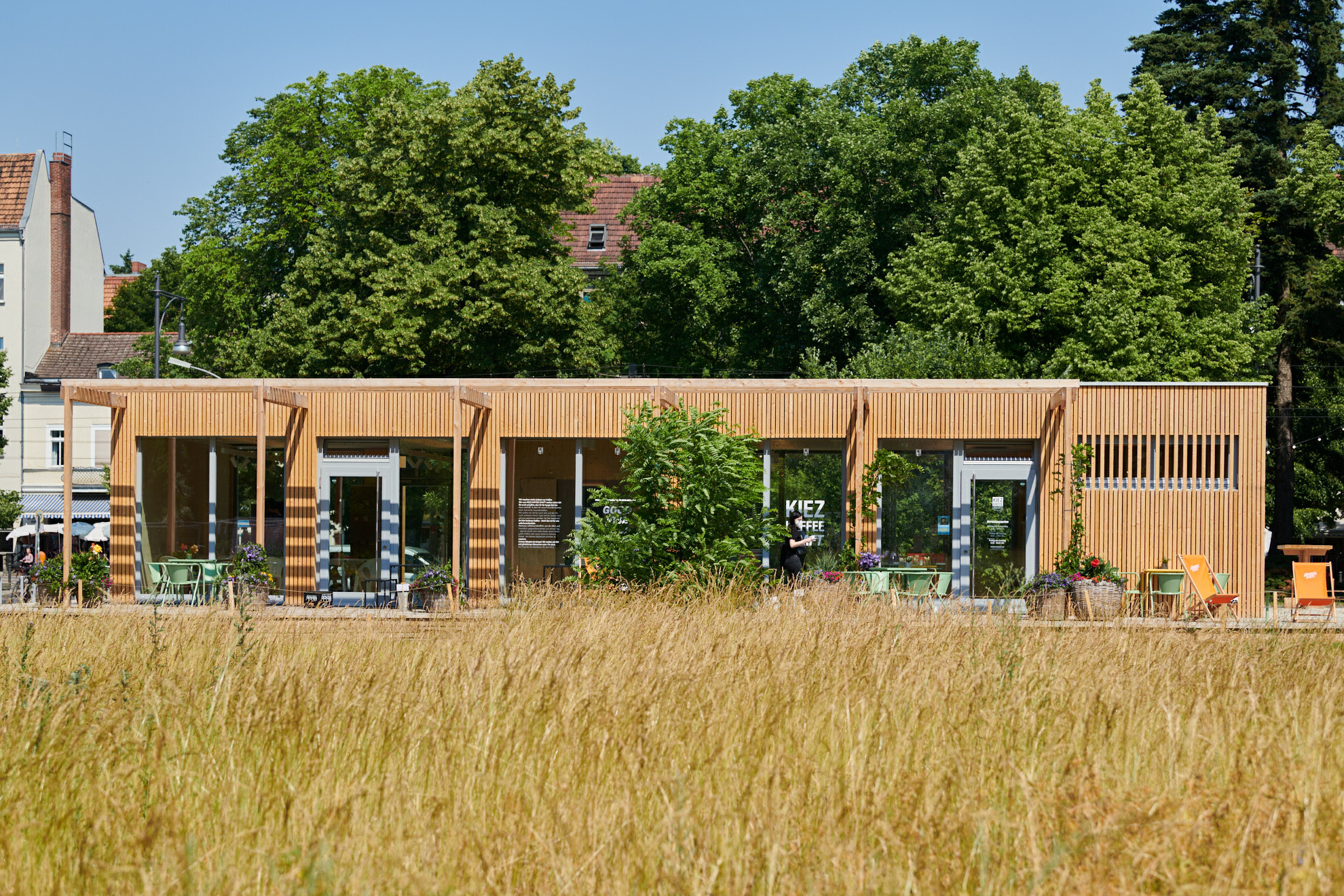 Der temporäre, eingeschossige Holzbau ist für eine breite Nutzungsvielfalt entworfen worden und bietet als Kiezcafé, Ausstellungs- und Mehrzweckraum sowie Co-Working-Space Raum für Begegnungen und Austausch.