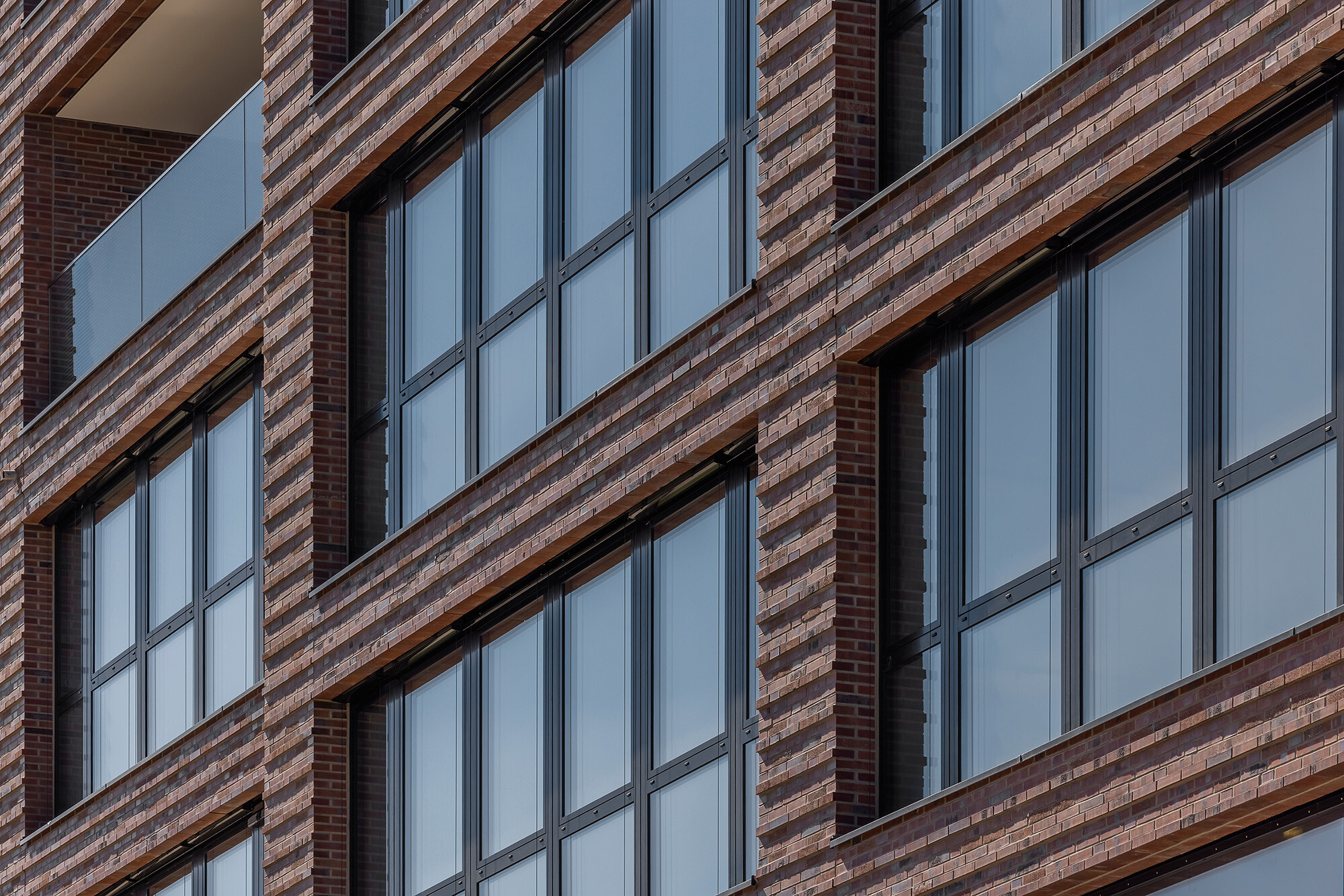 Das nördliche Haus am Platz wartet mit großflächigen, horizontalen Fensterbändern sowie expressiven Vor- und Rücksprüngen auf.