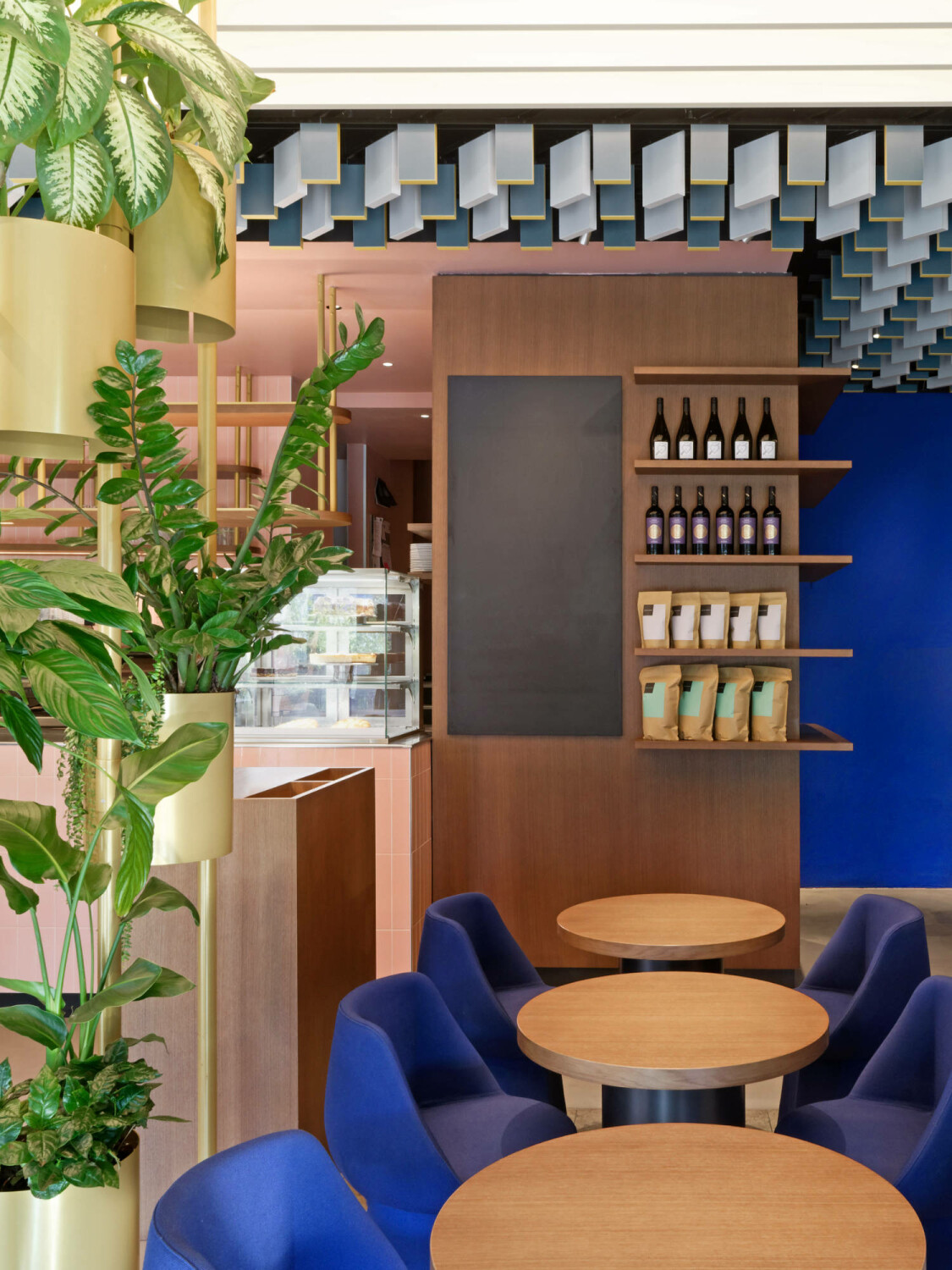 An runden Bistrotischen kann auf ultramarinblauen, gepolsterten Stühlen Platz genommen werden.