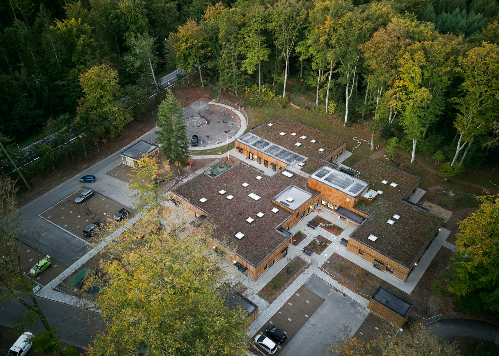 Der flache, eingeschossige Holzbau setzt sich aus ineinandergeschachtelten Quadern zu einem Baukörper mit zentralem Flur zusammen. Leicht unterschiedliche Gebäudehöhen machen die innere Aufteilung in mehrere Bereiche nach außen sichtbar.