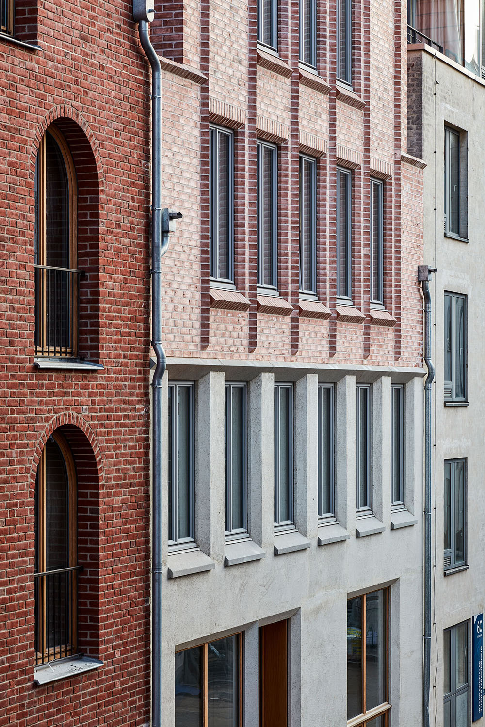 Die straßenseitige Gebäudehülle ist in einen zweigeschossigen Sockel aus Sichtbeton und ein Verblendmauerwerk aus rotem Backstein in den Obergeschossen gegliedert. 
