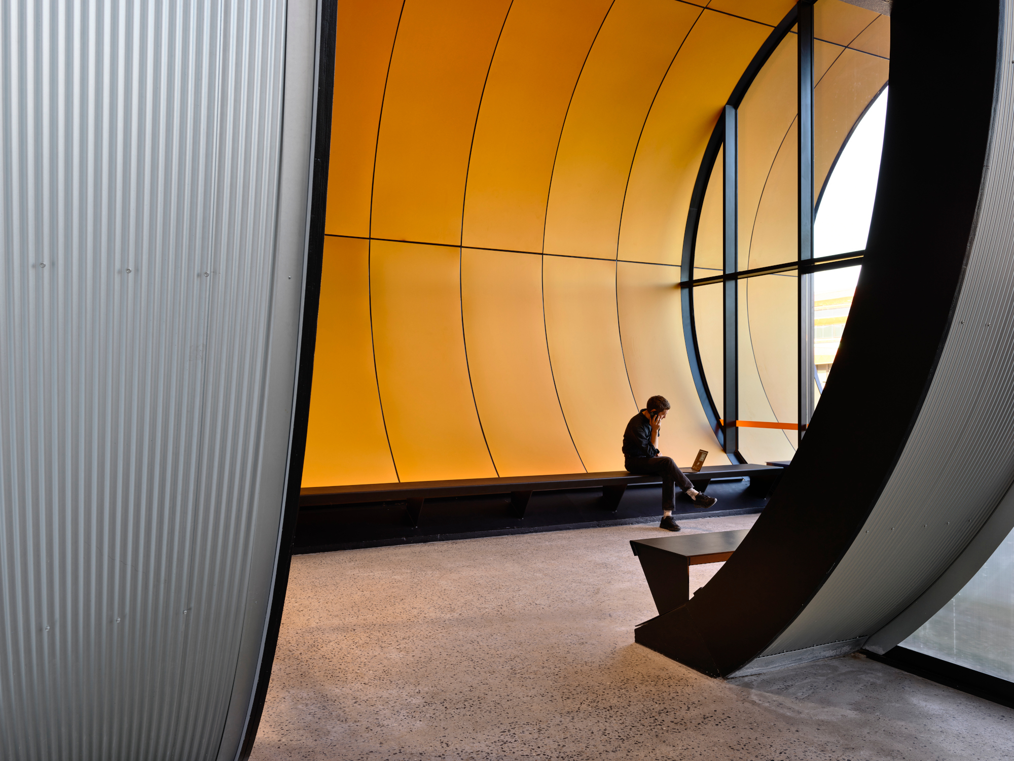 Einer der Tunnel ist als Eingangselement vorgesehen und wartet mit einer orangefarbenen Aluminiumverkleidung und raumhohen Glasfronten auf. 