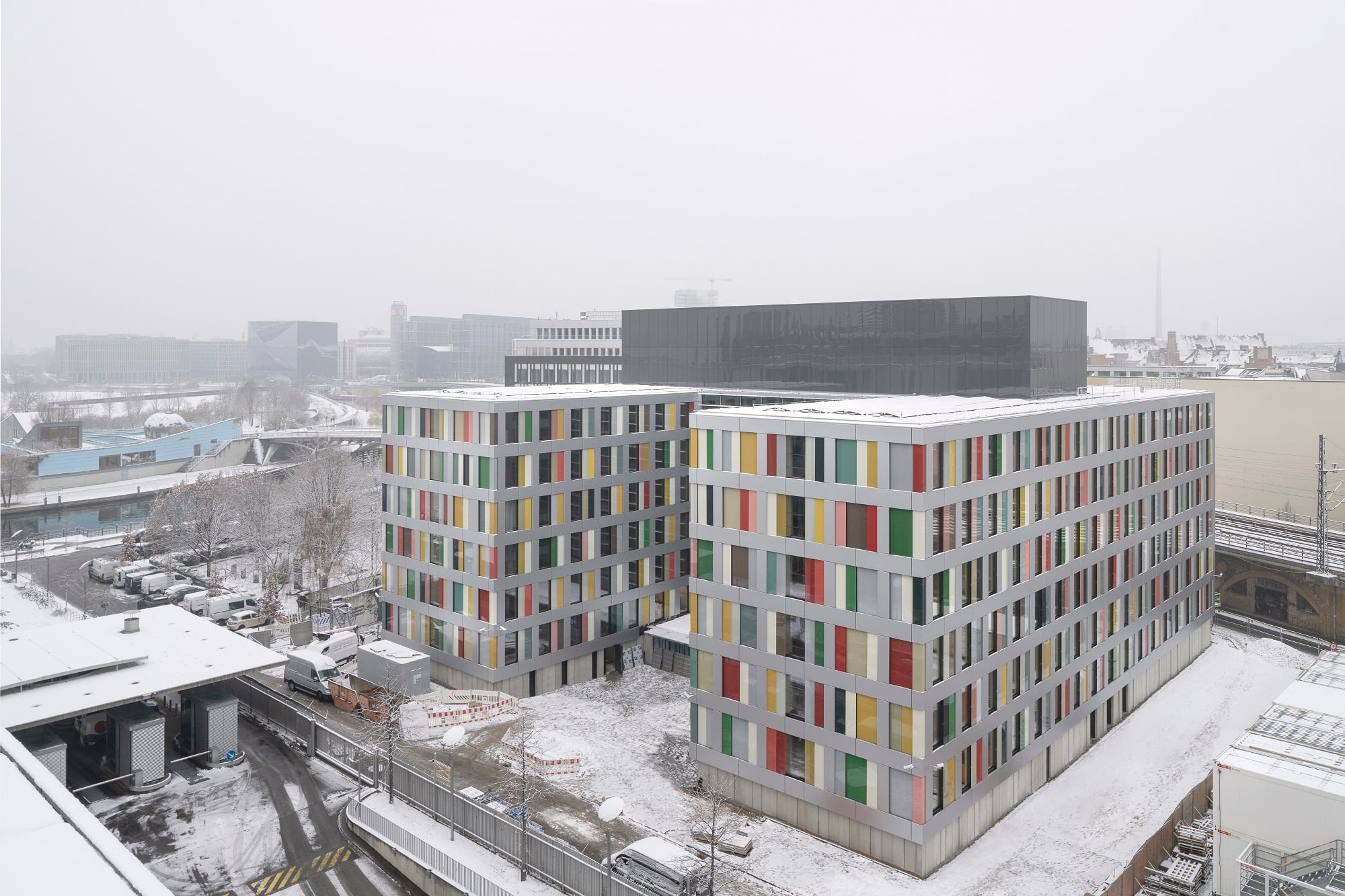 Auf einem Erdgeschoss aus Beton erheben sich sechs Geschosse in modularer Holzbauweise. Durch einen H-förmigen Grundriss entstehen Höfe gen Norden und Süden.