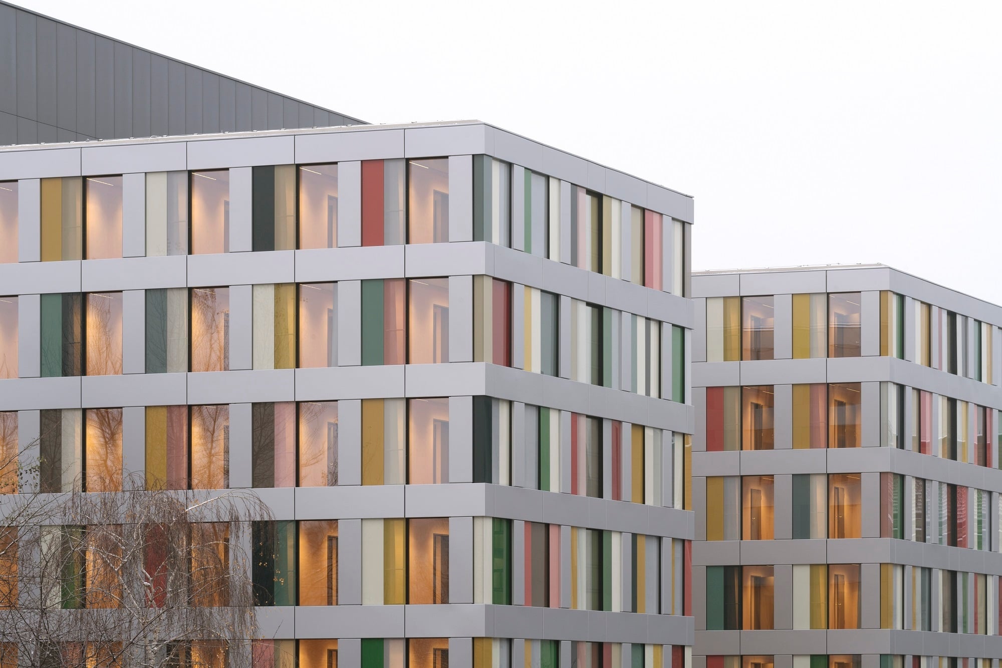Farbige Glaselemente und eine vorgehängte Aluminiumfassade lösen das strenge Raster der modularen Ordnung auf.