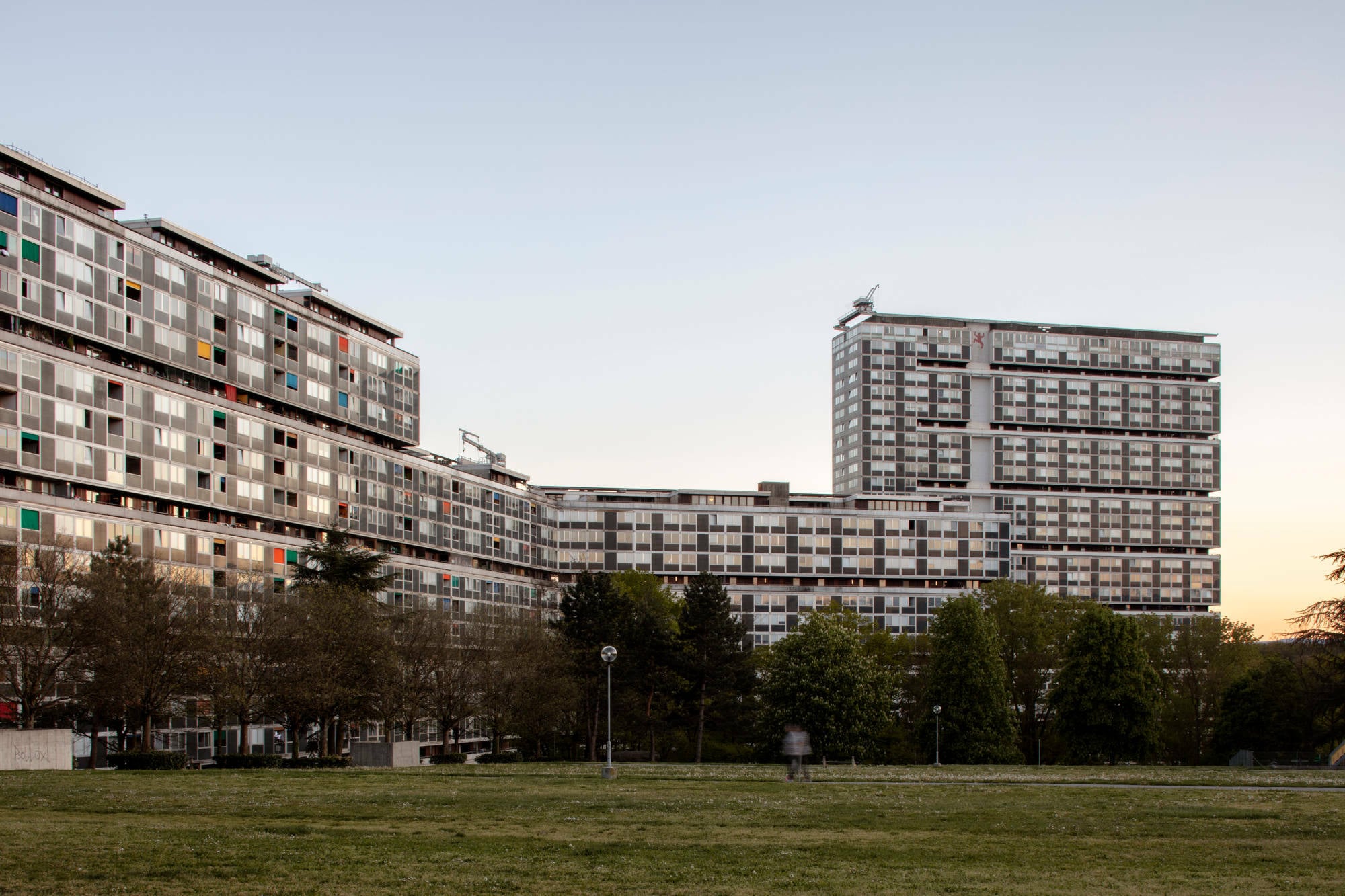 Westlich von Genf befindet sich die Großwohnsiedlung bestehend aus zwei Türmen, einem mehrfach geknickten, bandartigen Gebäude und einem Stadtteilzentrum.