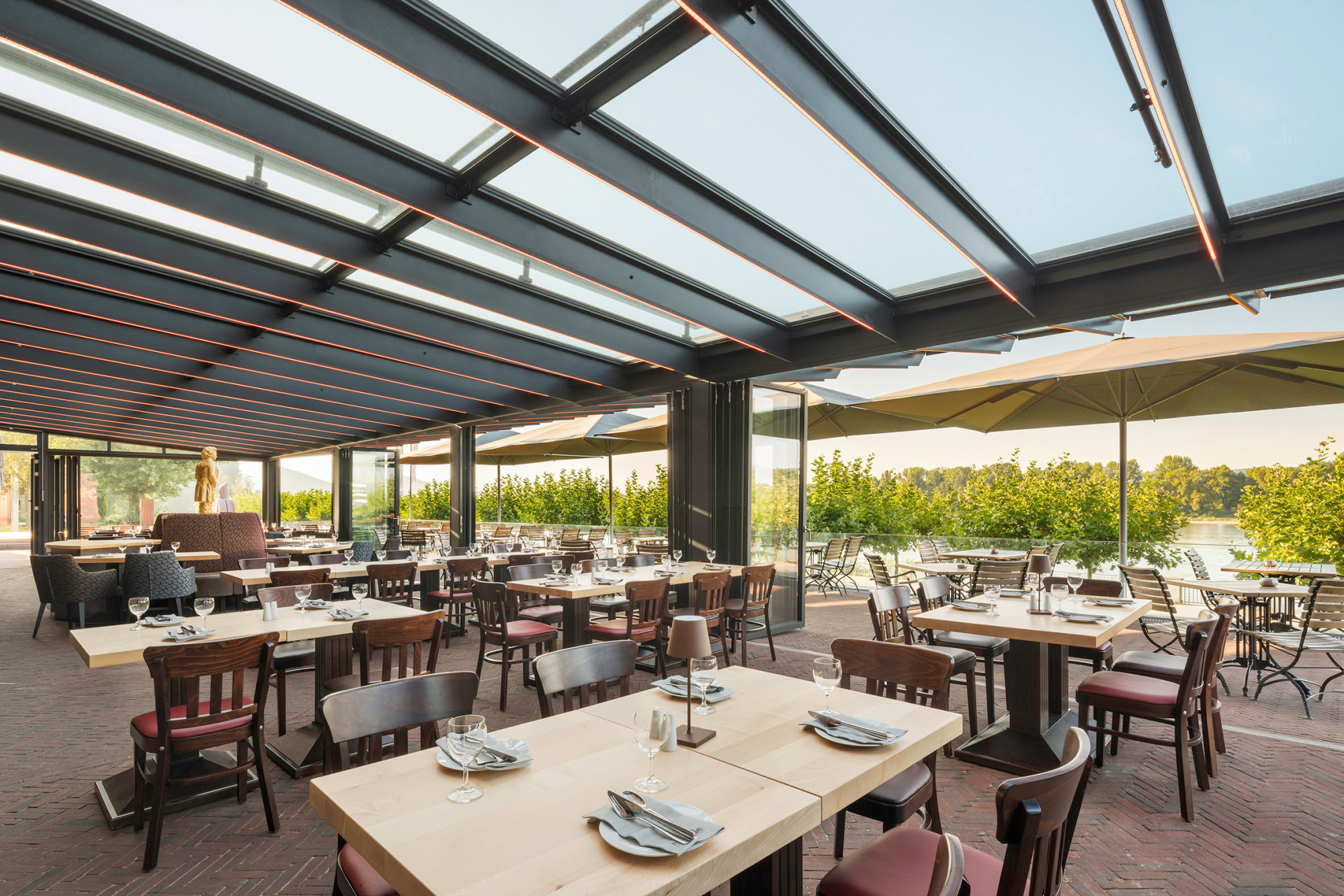 Während das Dach aus einer Stahlkonstruktion besteht, kommen als Wände bewegliche Glasfassaden zum Einsatz: die Glas-Faltwand-Systeme Highline und Ecoline von Solarlux.