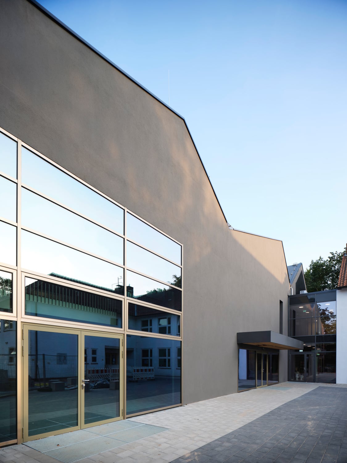 In der dunkelgrauen Putzfassade glänzen die großflächigen Fenster mit Rahmen aus eloxiertem Aluminium und farbneutraler Sonnenschutzverglasung. Die nordwestliche Gebäudeecke vor dem Saal der Oberstufenmensa verfügt über eine Pfosten-Riegel-Fassade.