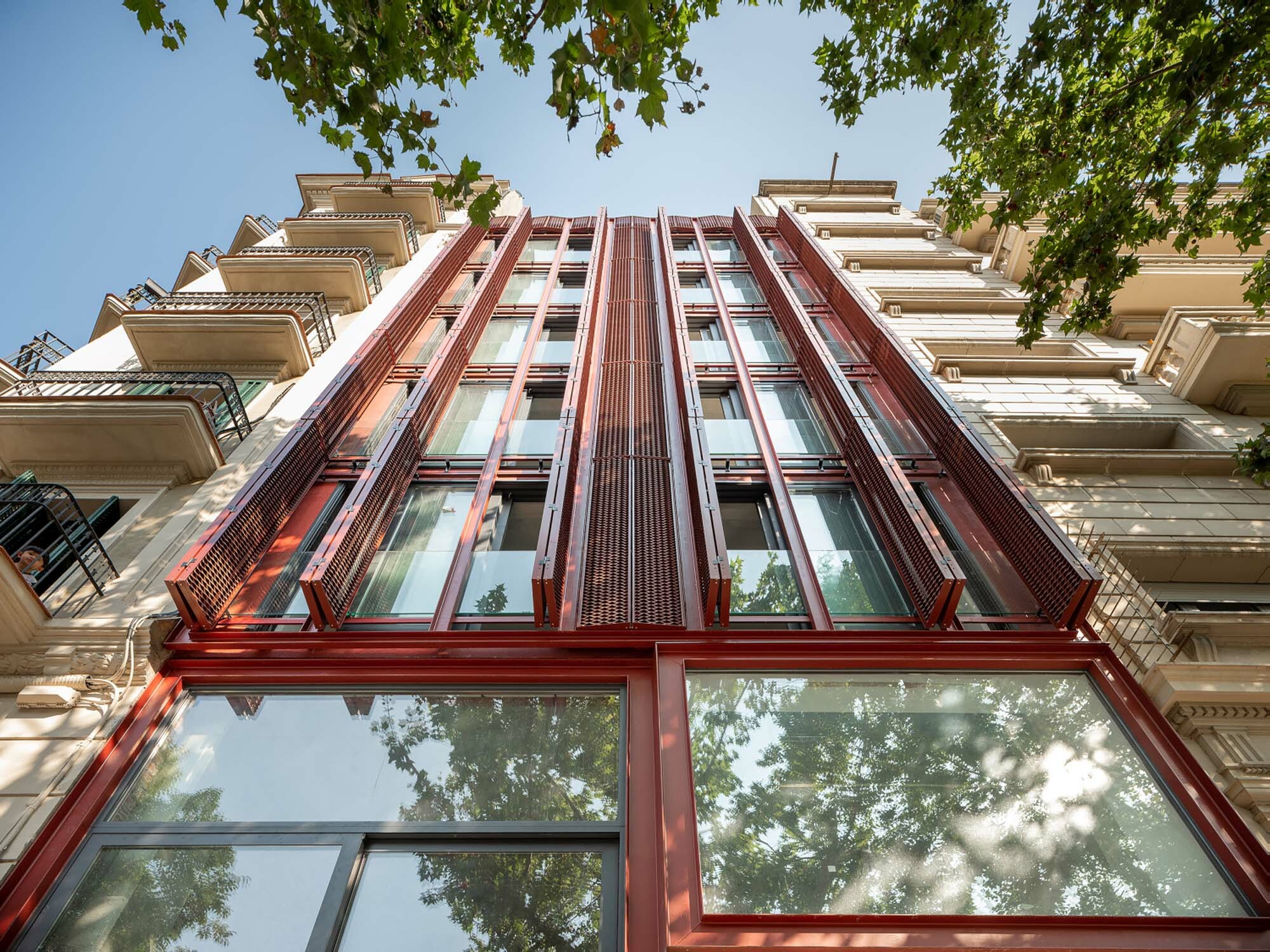 Rote Stahlträger und Streckmetallgitter als Sicht- und Sonnenschutz kennzeichnen die Fassade.