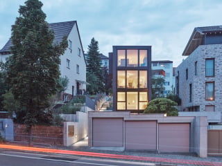 Das Stadthaus von Loweg Architekten ragt als schlanker, von dunklen Ziegeln eingefasster Turm aus Glas empor.