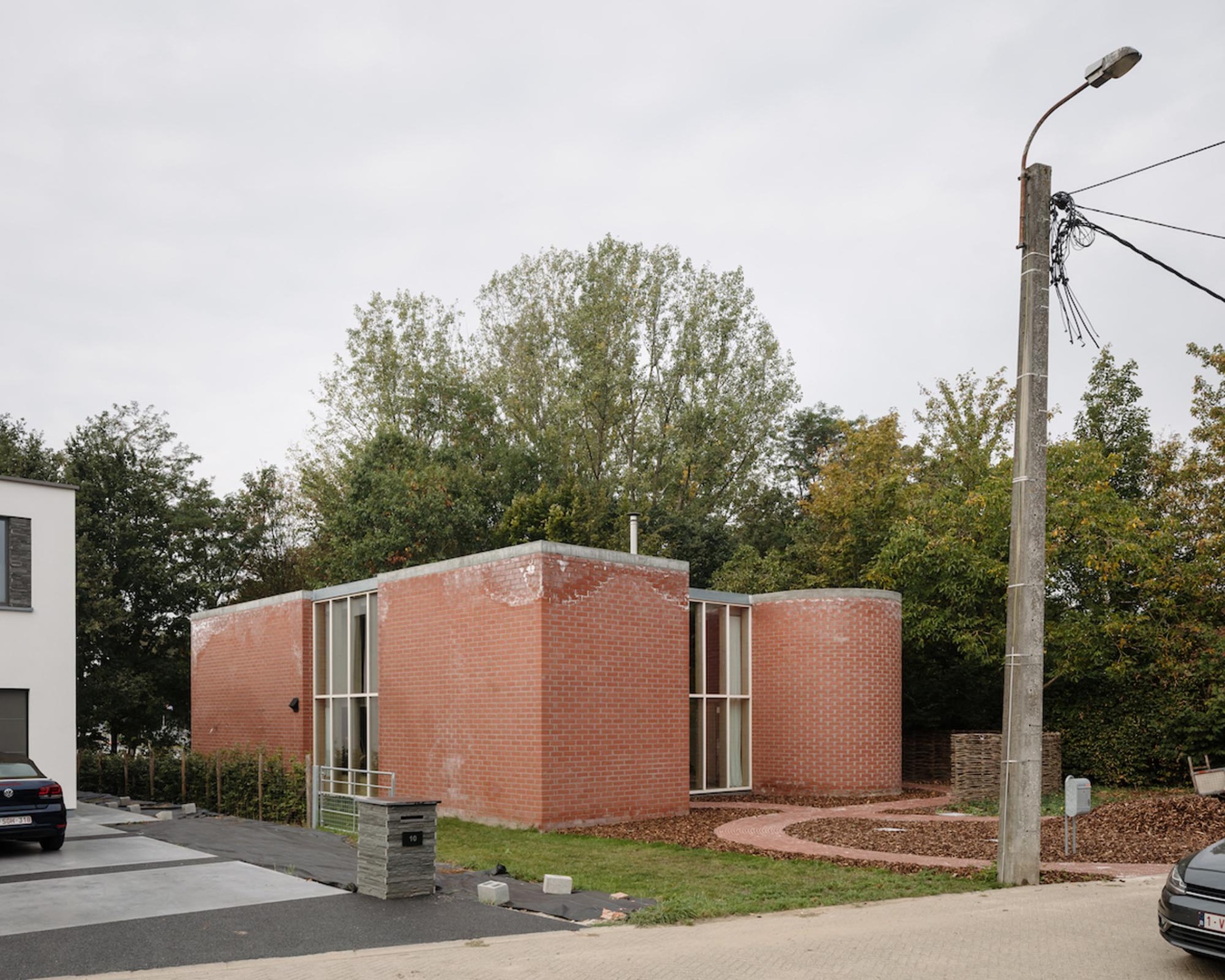 Das zweigeschossige Haus basiert auf einem quadratischen Grundriss, dessen Eckpunkte von vier gemauerten Volumina markiert werden, die jeweils als Halbkreise bzw. Rechtecke aus dem Quadrat hinaustreten.