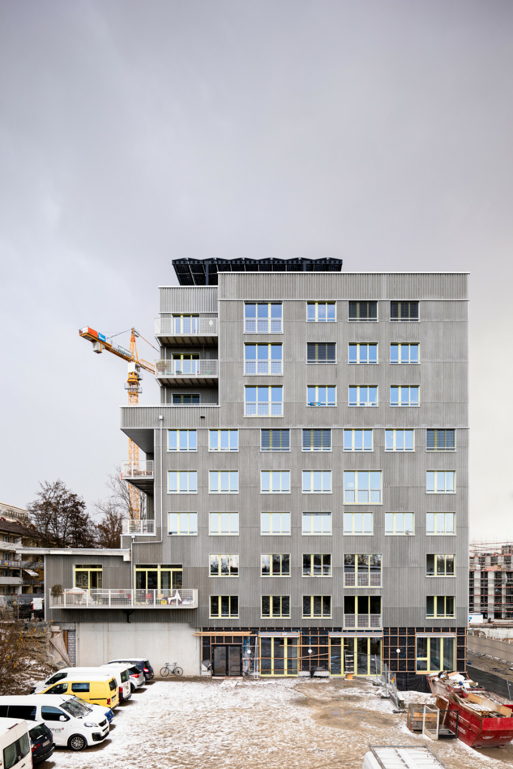 Ansicht Nordwest: Den oberen Abschluss bildet eine gemeinschaftlich nutzbare Dachterrasse, verschattet von Photovoltaik-Modulen.