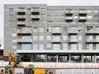Die ehemalige Lagerhalle wurde um drei Geschosse in Holzbauweise aufgestockt. Mit der Fassade aus gewellten Faserzementplatten kontrastieren gelbe Fensterprofile (Südwestansicht).