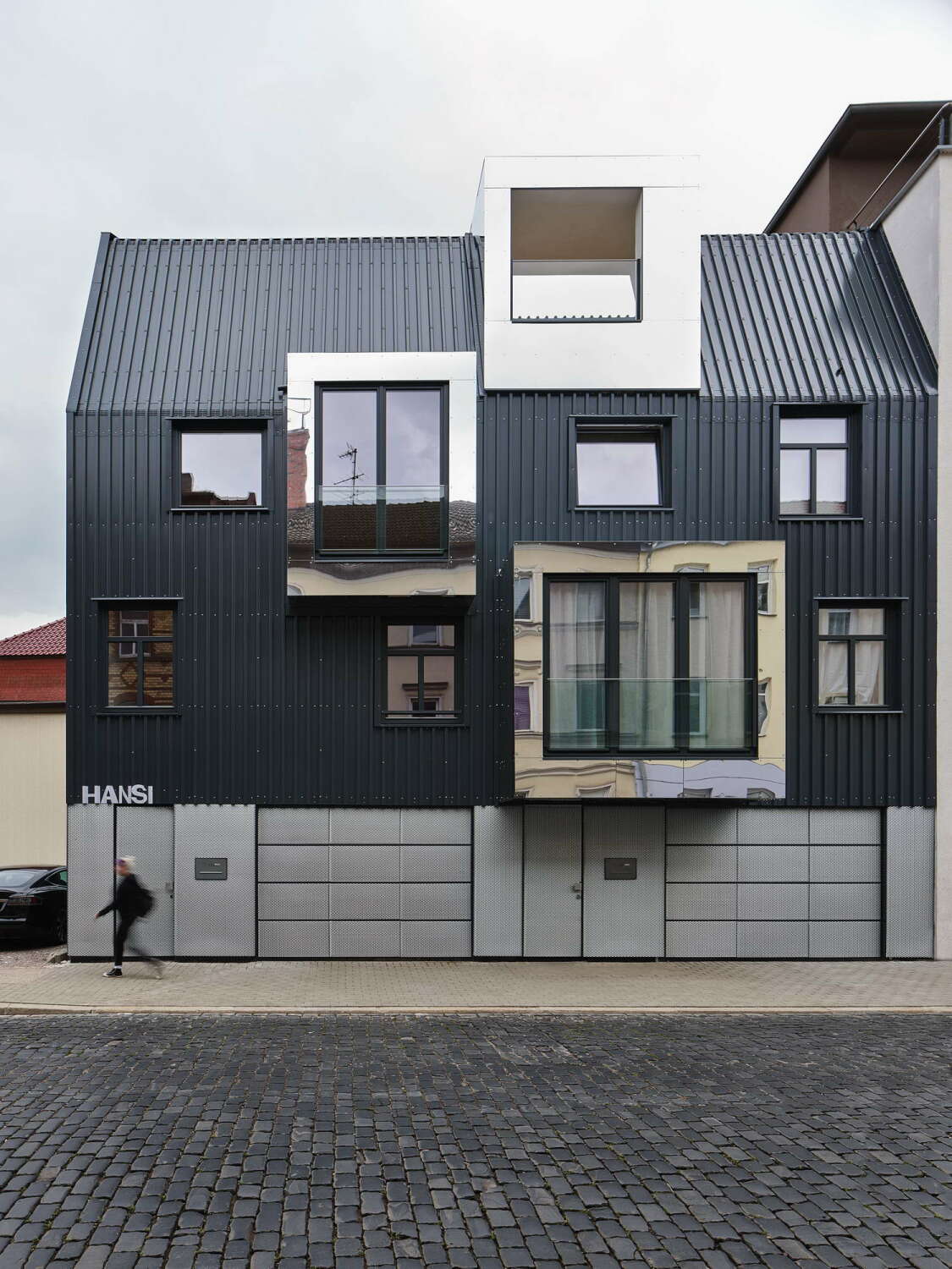 Außen ist das Haus mit dunklem Trapezblech verkleidet – ein selbstbewusster Bezug zum „Blechbüchsenviertel“, wie die Gegend im Volksmund genannt wurde.