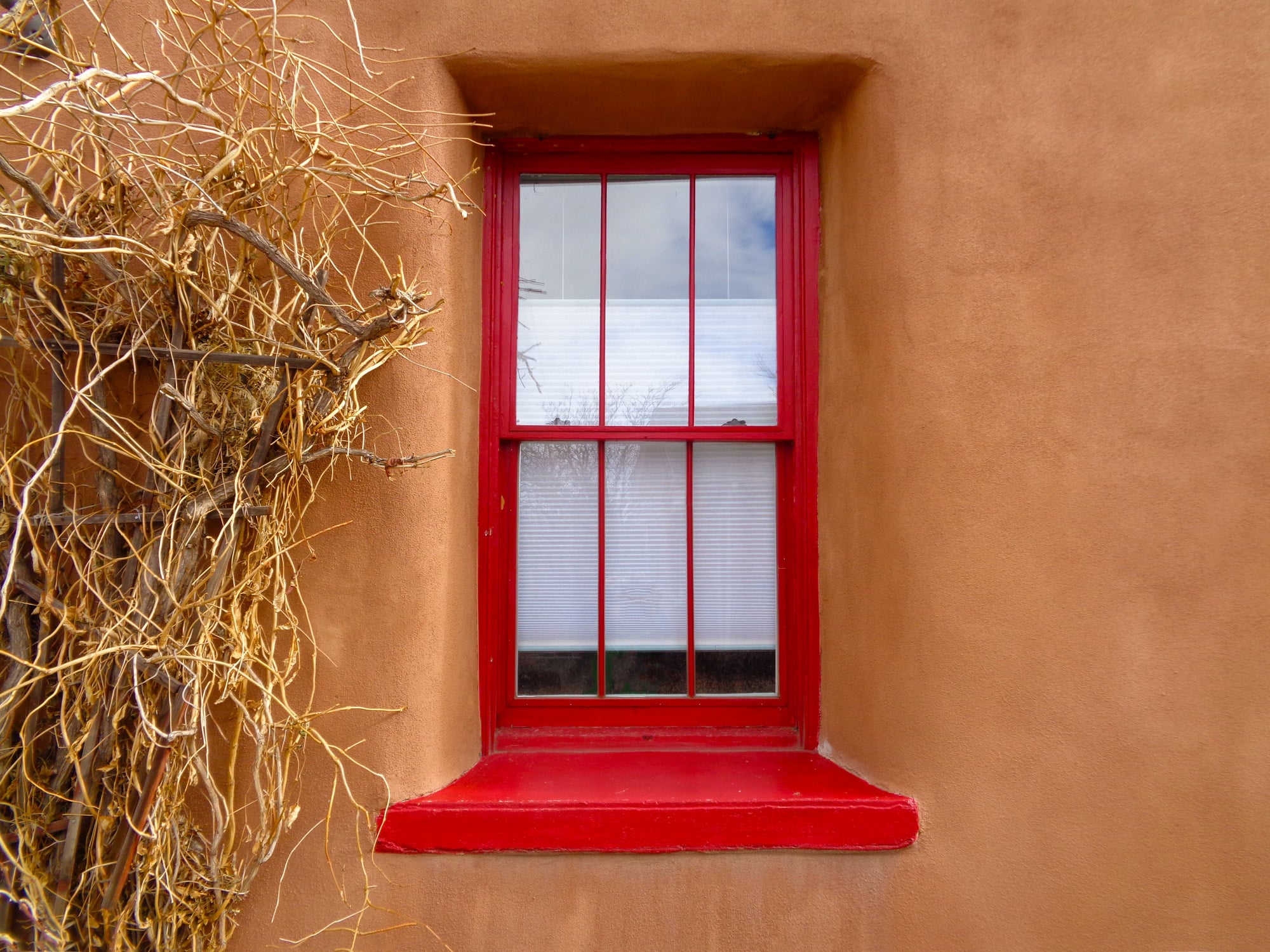 Hölzernes Vertikalschiebefenster mit einer 3x3-Sprossenteilung in einer Adobe-Wand in New Mexico 