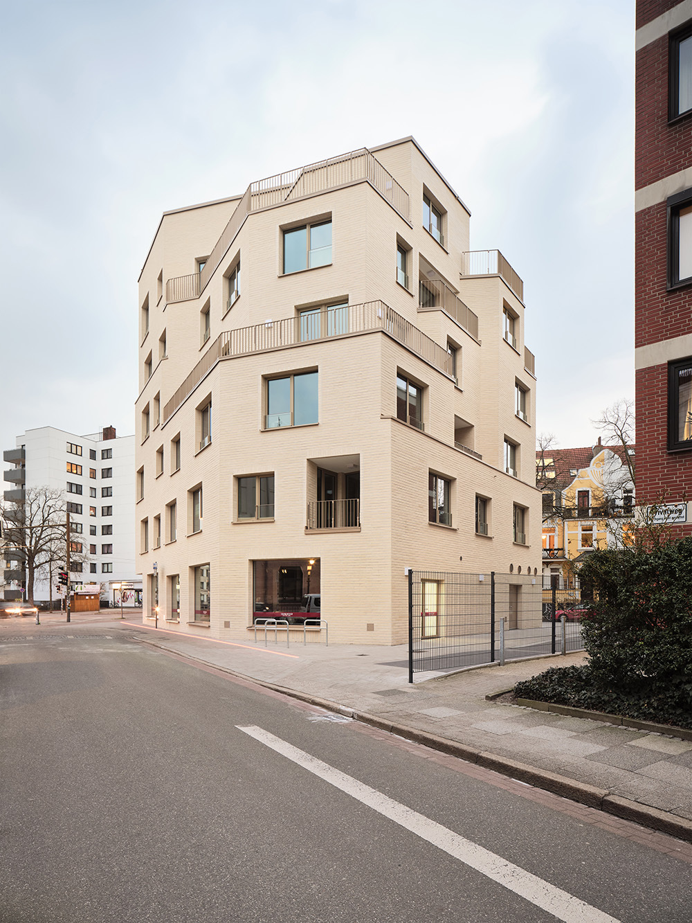 Die sechs Geschosse springen in Richtung der ruhigeren Seitenstraßen unregelmäßig zurück. Dadurch entstehen auf den einzelnen Stockwerken unterschiedlich große Außenbereiche. 