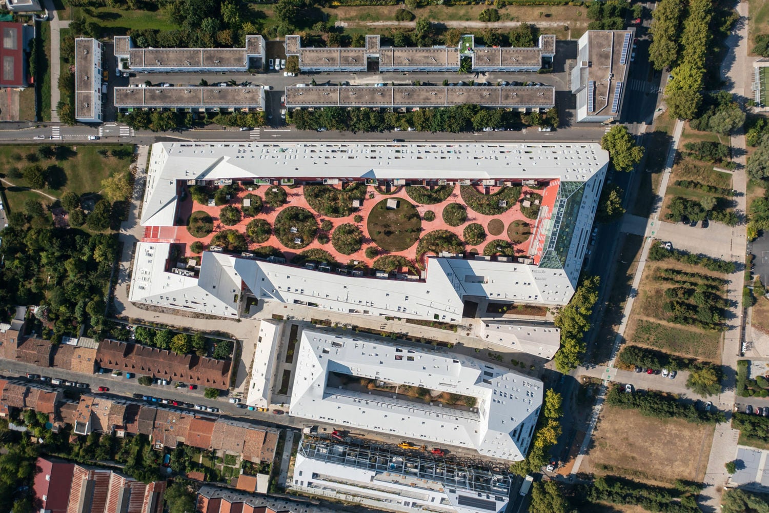 Das teils 200 Meter lange Gebäude füllt das Grundstück bis an seine Grenzen aus und umschließt einen öffentlich zugänglichen, begrünten Innenhof mit einer Fläche von 5.200 Quadratmetern. 