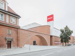 Ein gestaffelter Baukörper aus flachem Ziegelmauerwerk, gerundete Ecken, ein aufragender Bühnenturm, weithin sichtbar im Stadtraum: Das neue Volkstheater München befindet sich auf dem ehemaligen Viehhofgelände der Stadt.