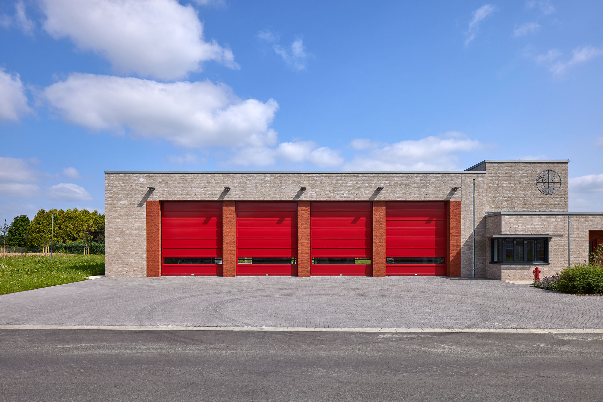 Das ein- und zweigeschossige Feuerwehrhaus steht am westlichen Rand der Gemeinde Wemb, am Übergang zu landwirtschaftlichen Flächen.