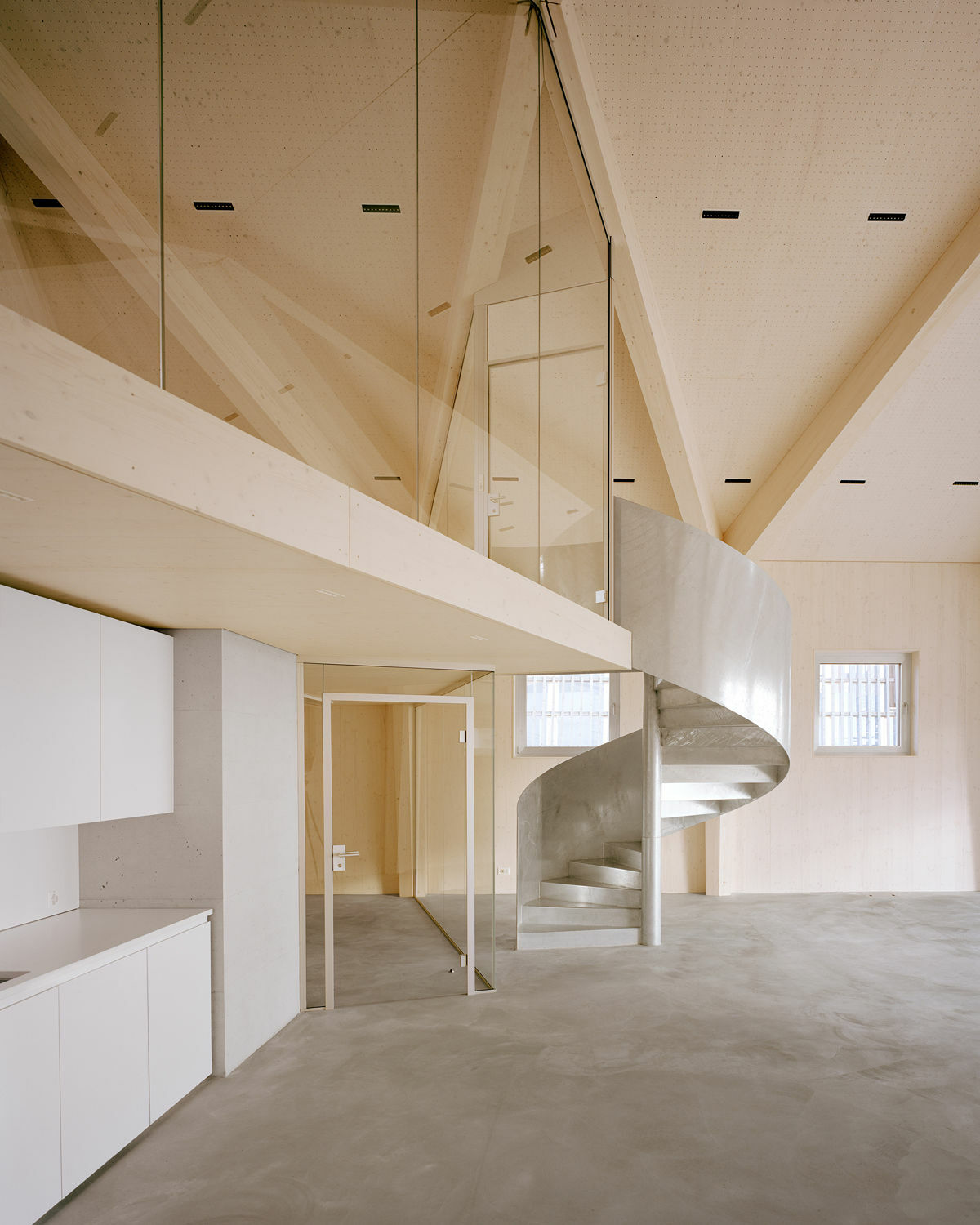 Eine Spindeltreppe aus feuerverzinktem Stahl hebt sich von der umgebenden Architektur ab.