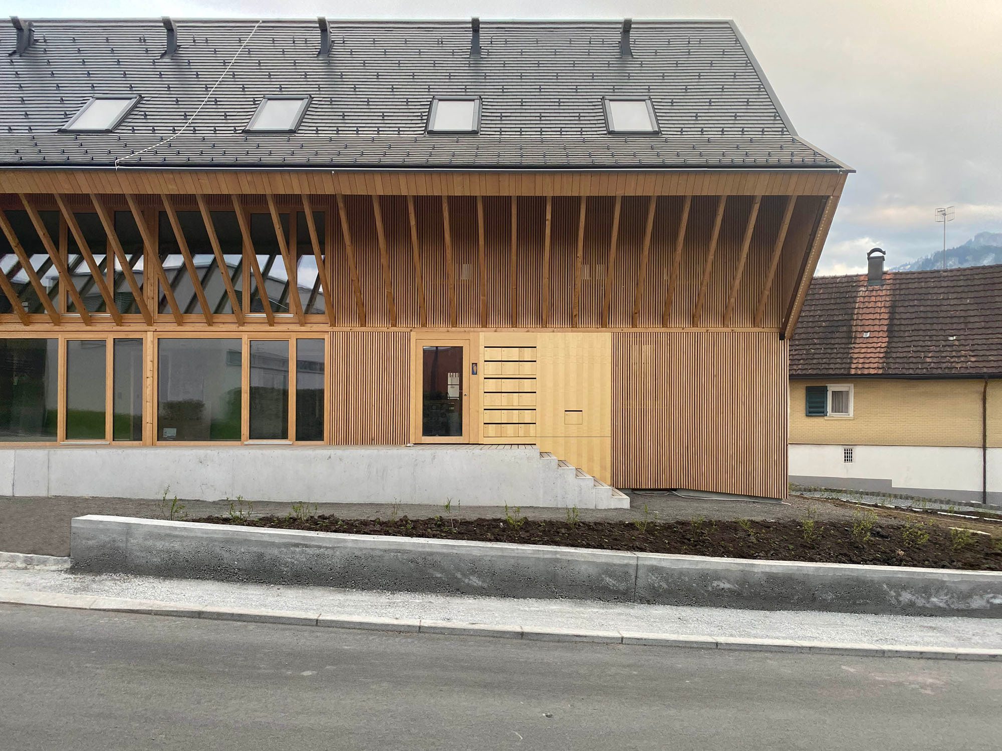 Das steile Giebeldach ist typisch für die lokale Bauweise. Die Architekten haben das Vordach über die ganze Hauslänge gezogen, damit der Eingang geschützt ist.