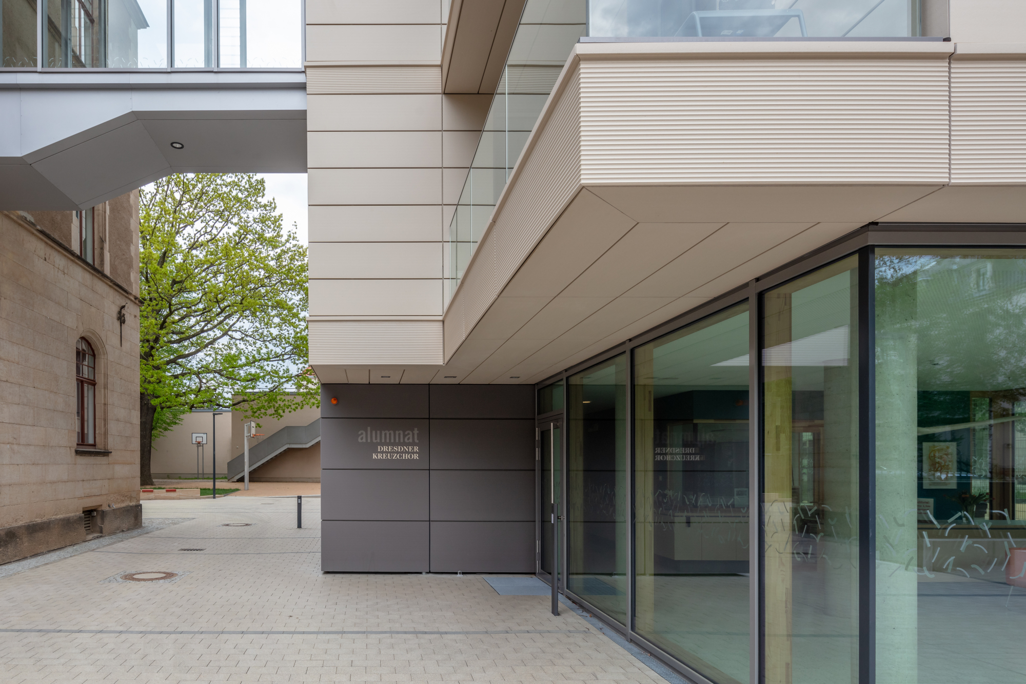 Mit seiner hinterlüfteten Keramikfassade nimmt der Neubau Bezug auf den Sandstein des Bestands