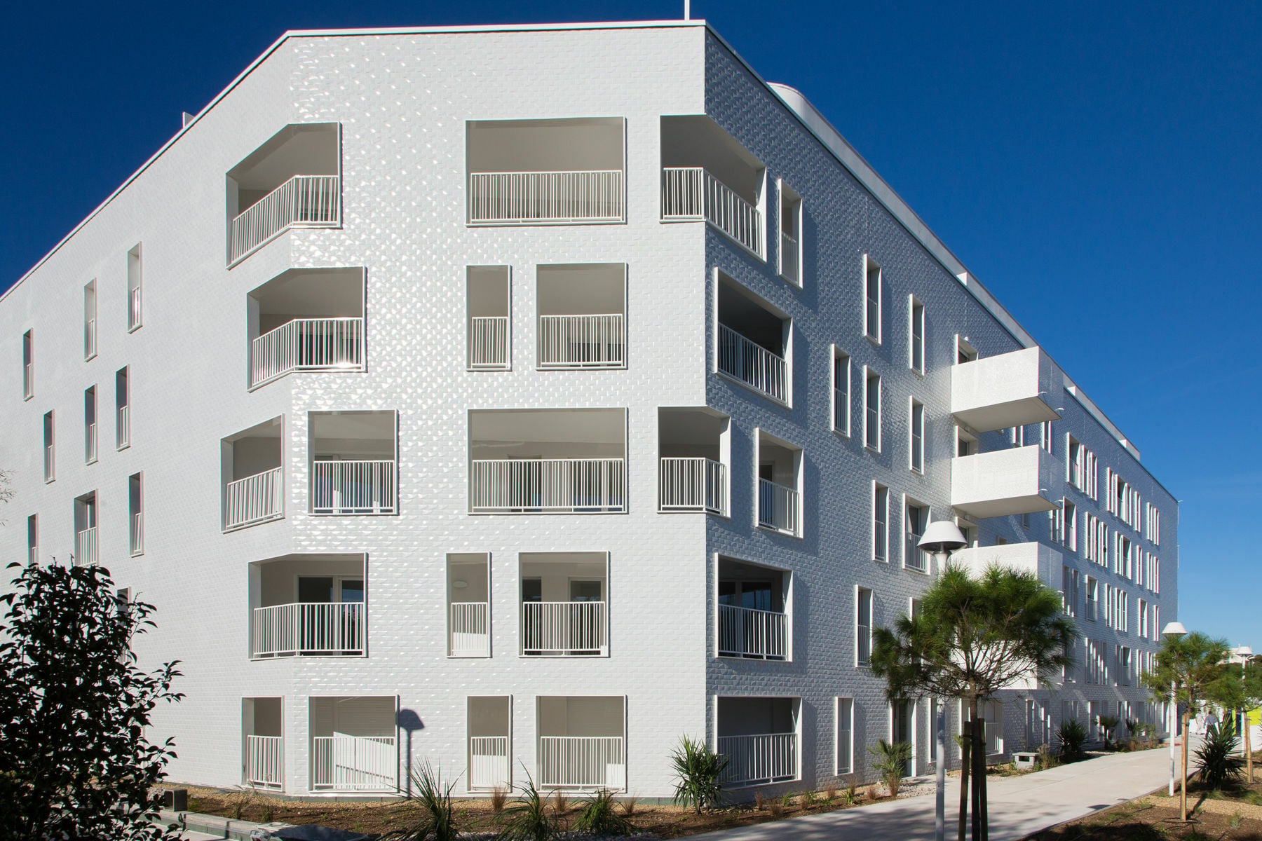 An der Nordostseite, wo sich ein Sportplatz befindet, präsentiert sich der Baukörper mit einer langen durchgehenden Fassade und scharfen Gebäudekanten.