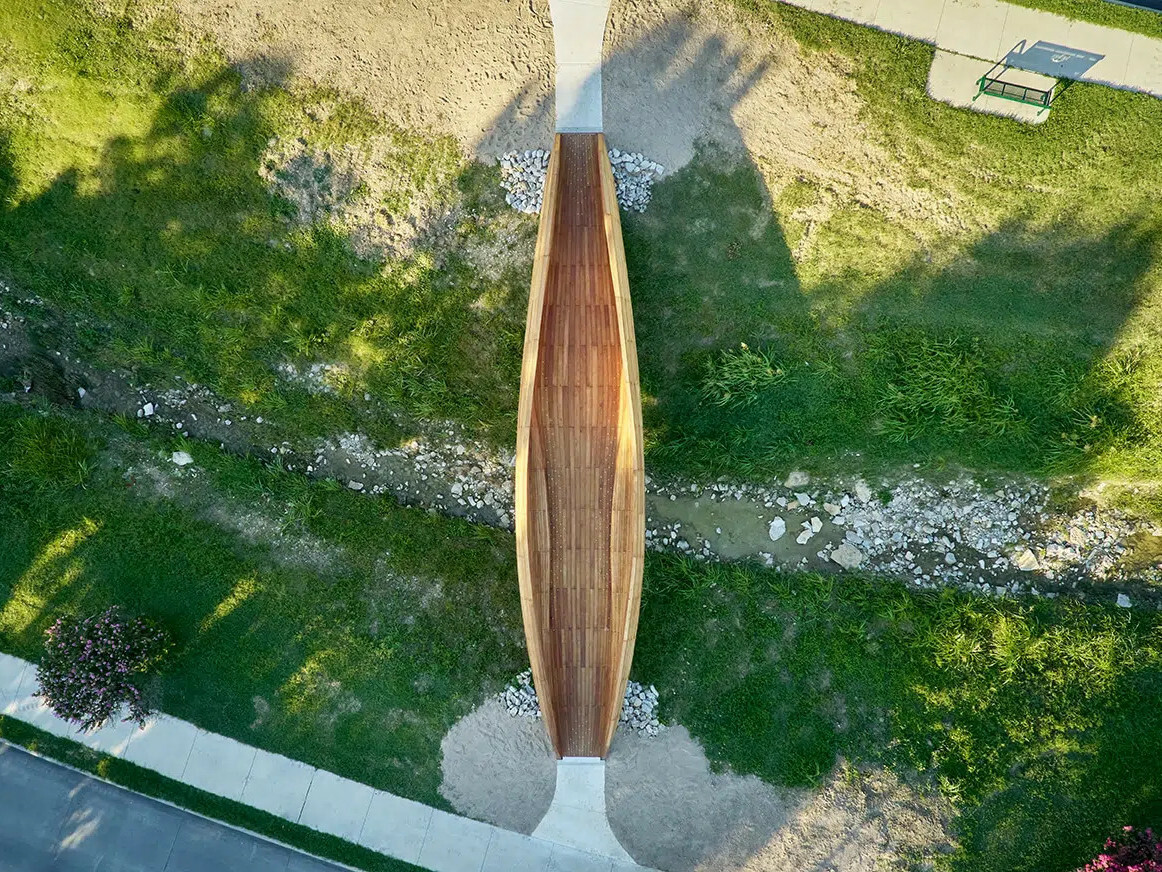 Die rund 19 Meter lange, organisch geformte Holzbrücke verbindet die Wohngebiete zu beiden Seiten des Ufers.