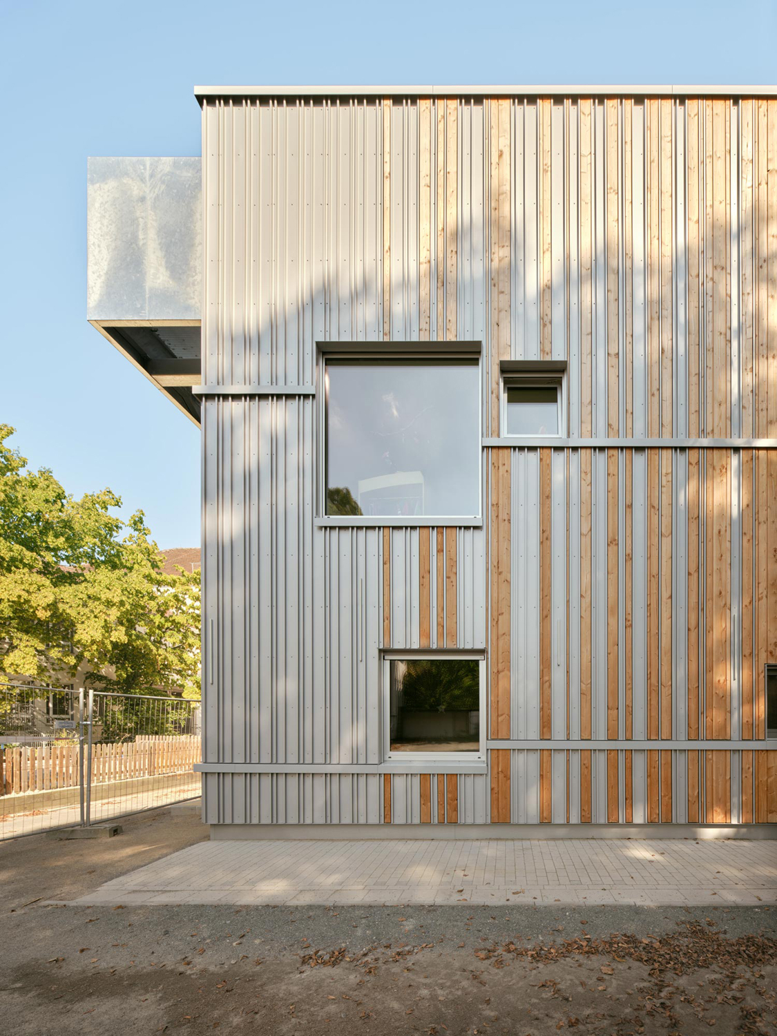 Die Holzfassade steht im visuellen Kontrast zu den gelben Wänden, Brüstungen und Bodenbelägen.