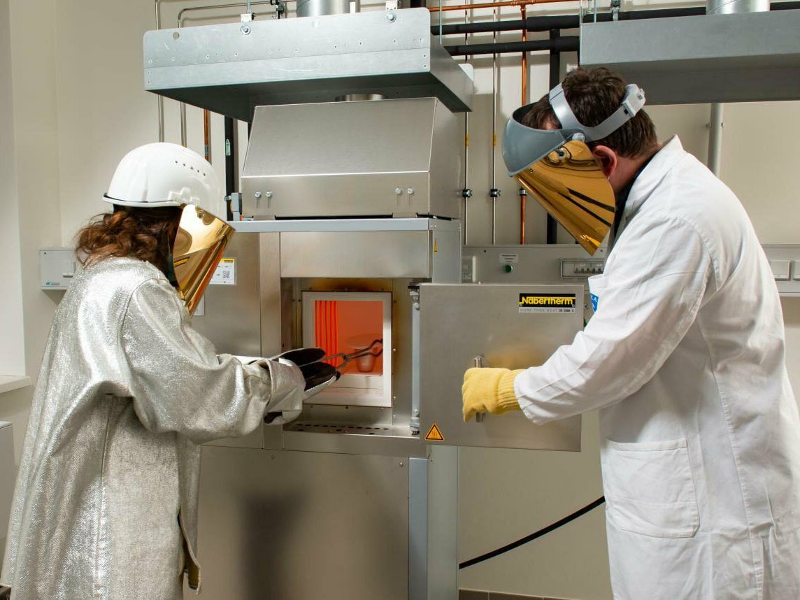 Forschende vor einem Ofen in den Versuchsanlagen für Glastechnologie an der TU Bergakademie Freiberg