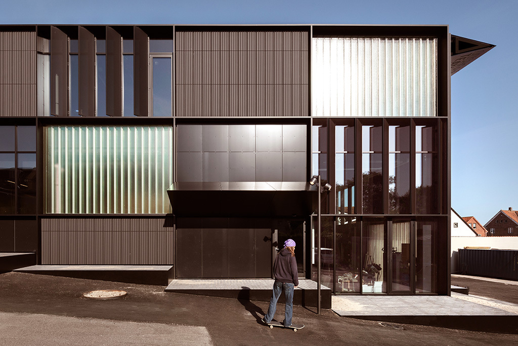An der Fassade wechseln schwarze Terrakottapaneele mit transparenten und transluzenten Glasflächen.